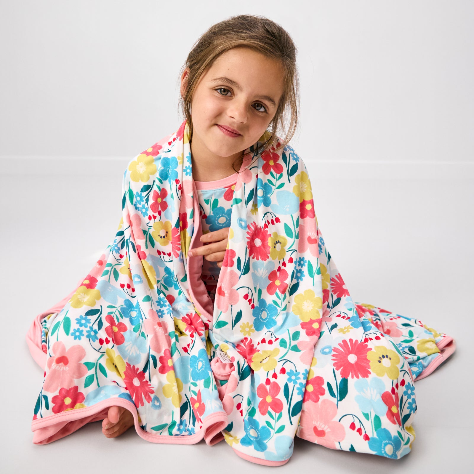 Sitting girl wrapped in the Midsummer Meadow Large Cloud Blanket®