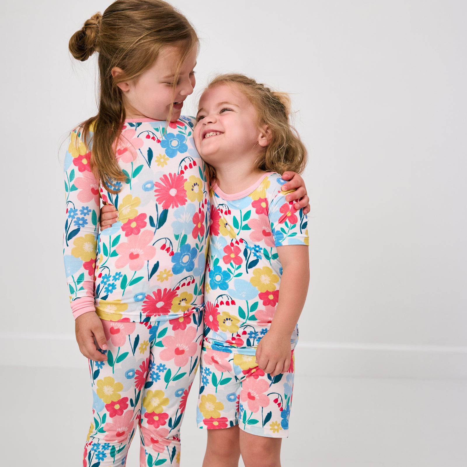 Two girls wearing matching two-piece floral pajama sets
