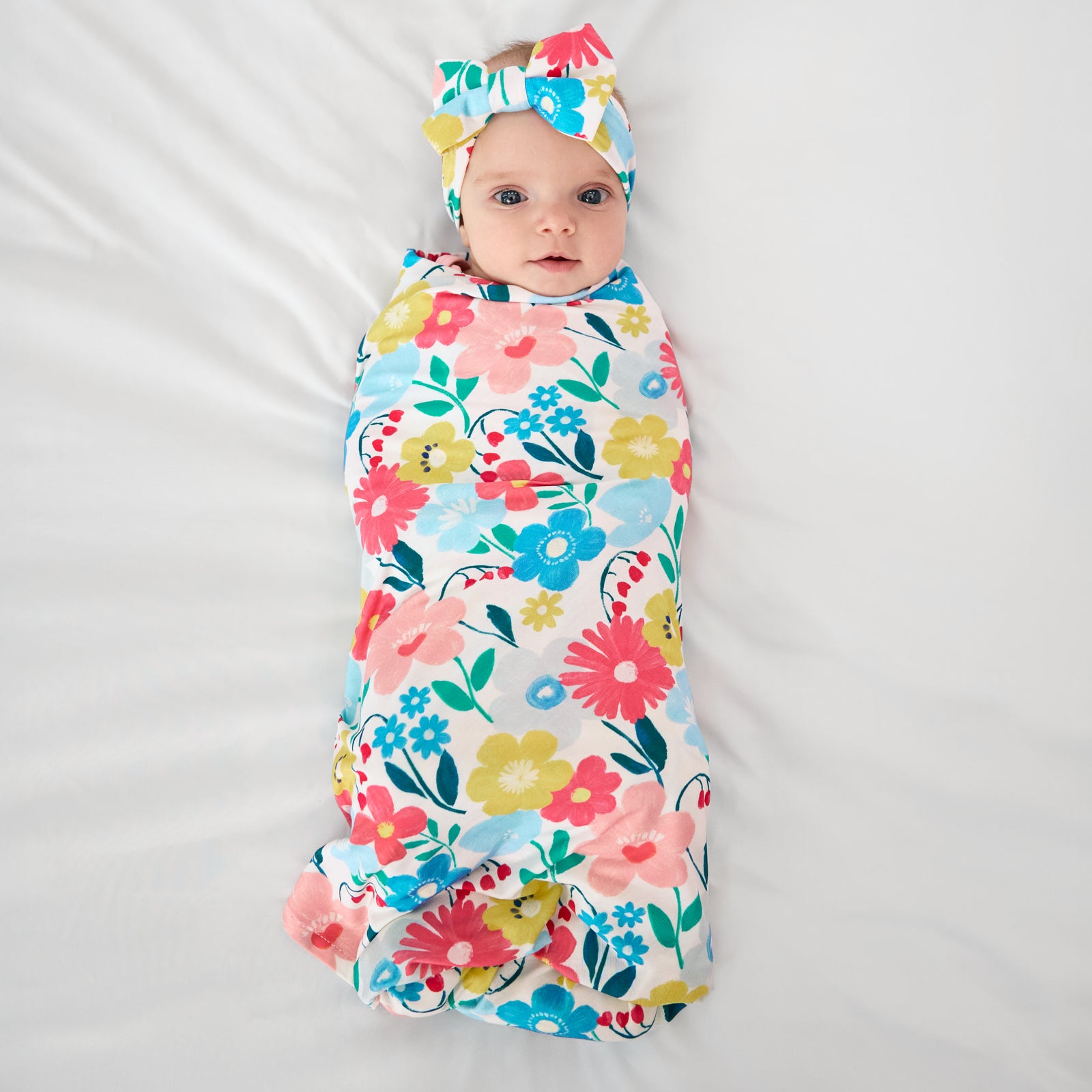 Aerial view of baby wearing the Midsummer Meadow Swaddle & Luxe Bow Headband Set