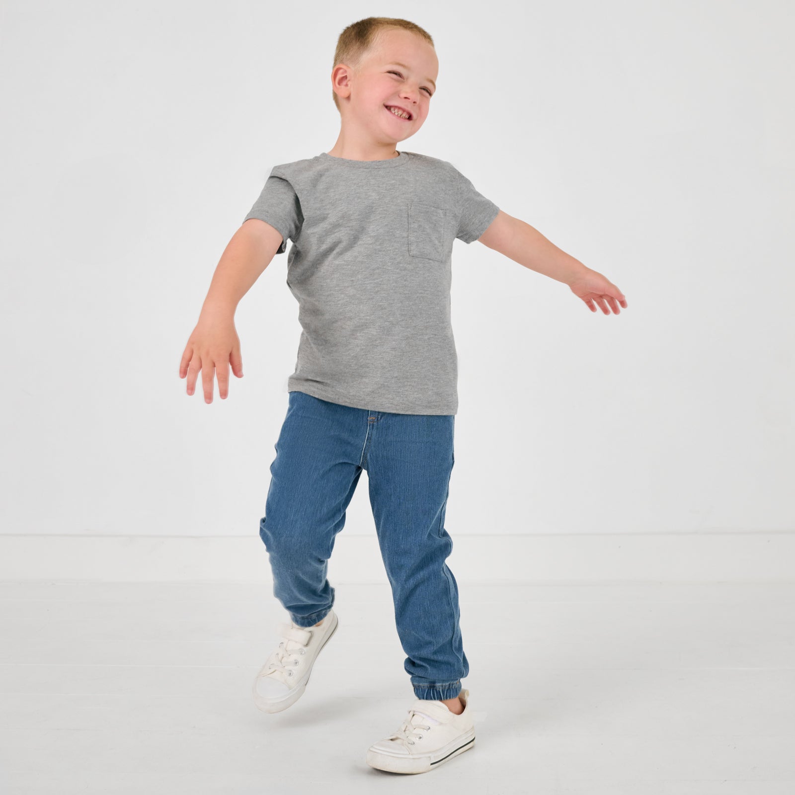 Child in motion wearing the Midwash Blue Denim Jogger with a gray boys shirt