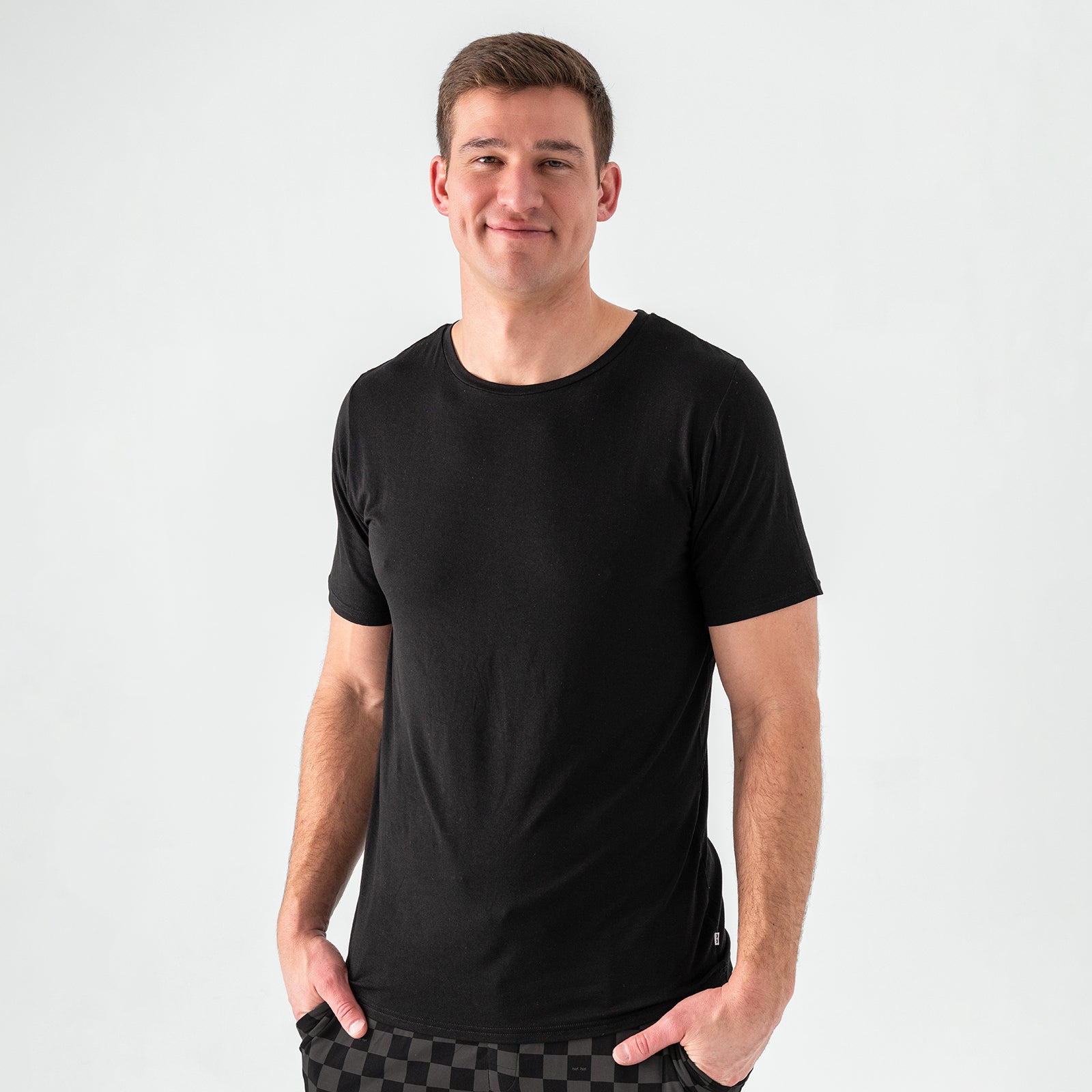 Man wearing the Men's Black Short Sleeve Pajama Top with Monochrome Checks Pajama Pants