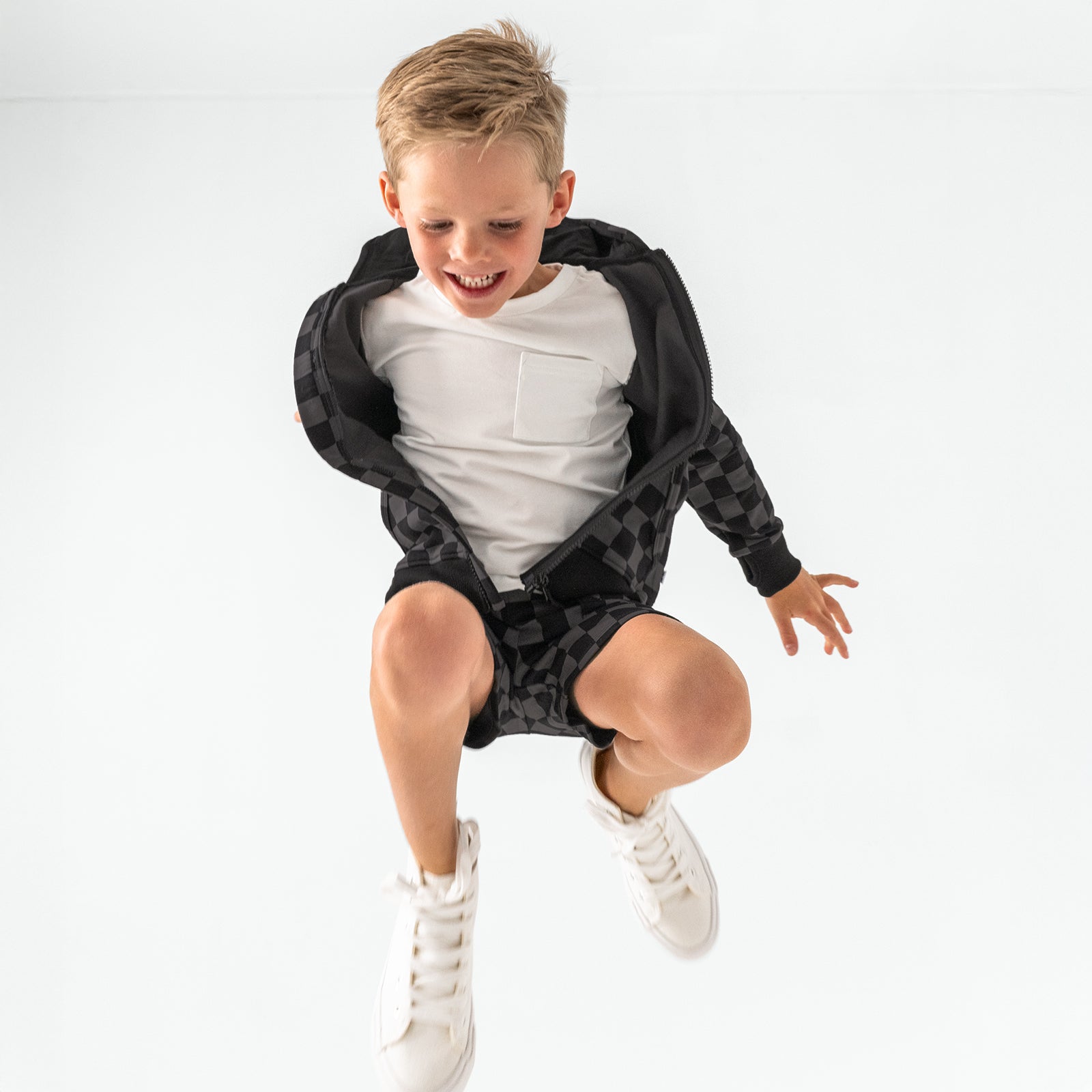 Jumping child wearing the Monochrome Checks Shorts and matching zip hoodie