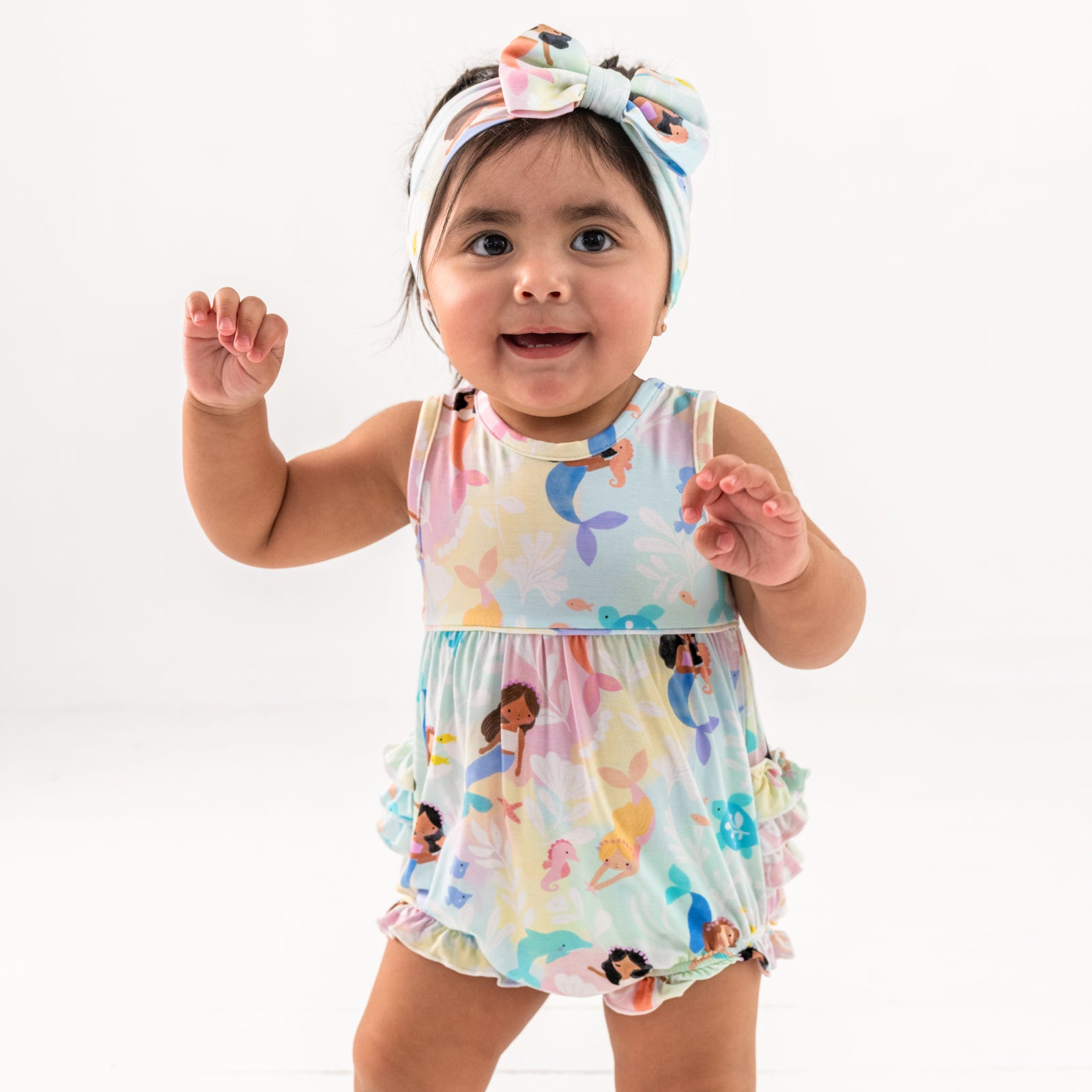Standing child wearing the Mystic Mermaids Bubble Romper and luxe bow headband