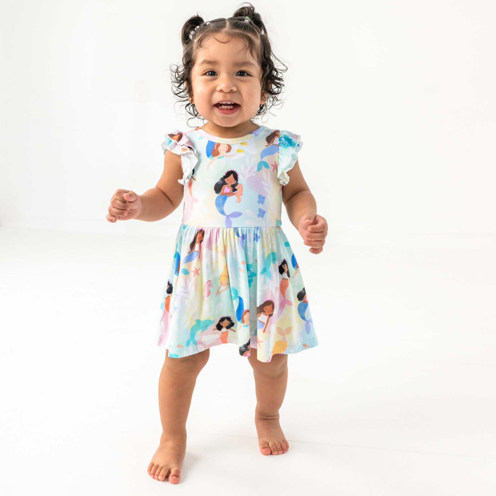 Standing child wearing the Mystic Mermaids Flutter Twirl Dress with Bodysuit