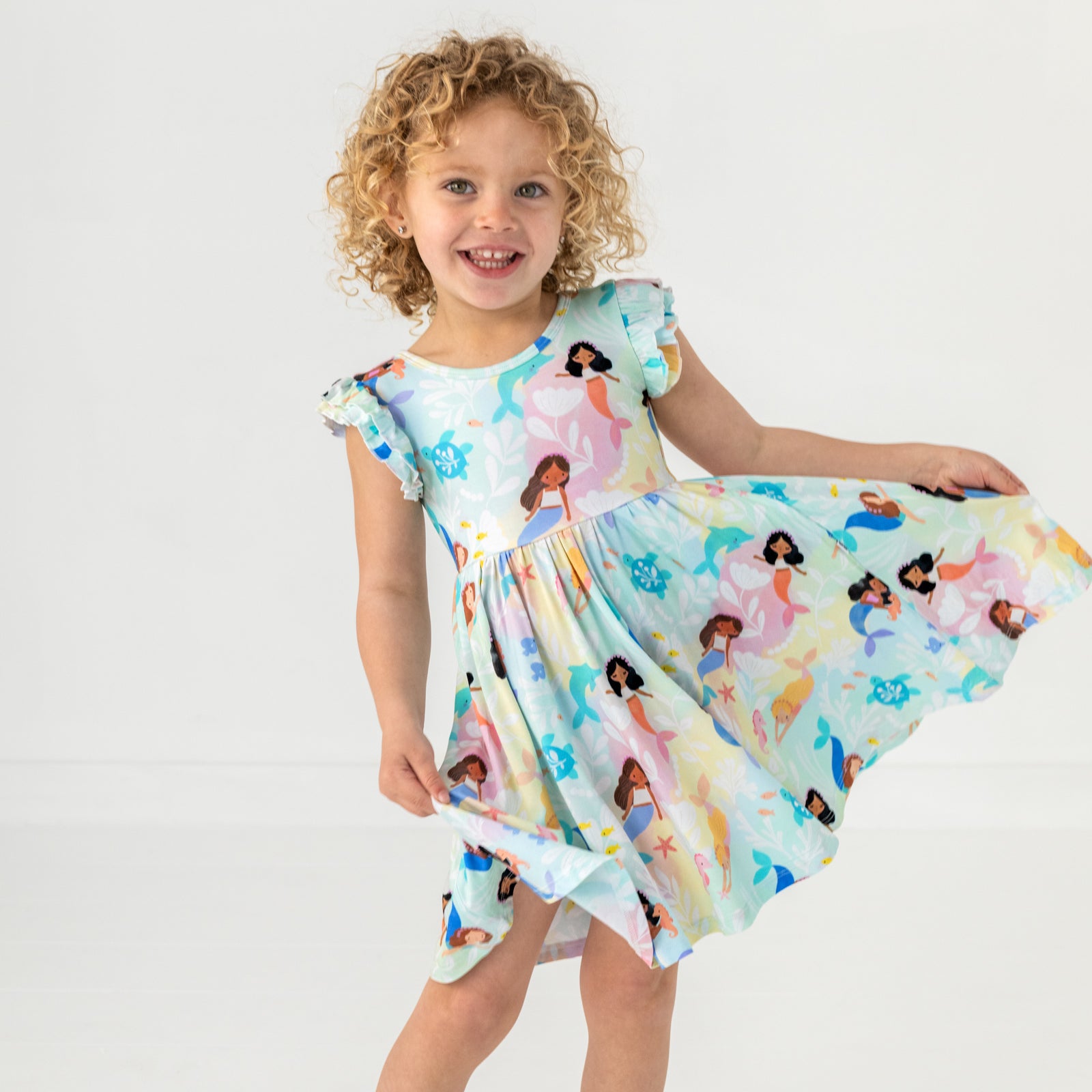 Posing child wearing the Mystic Mermaids Flutter Twirl Dress