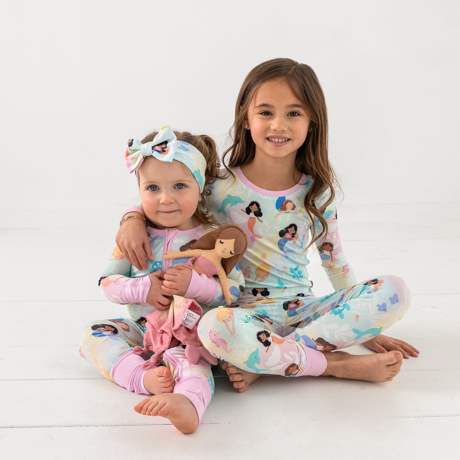 Two sitting children wearing matching Mystic Mermaids pajamas