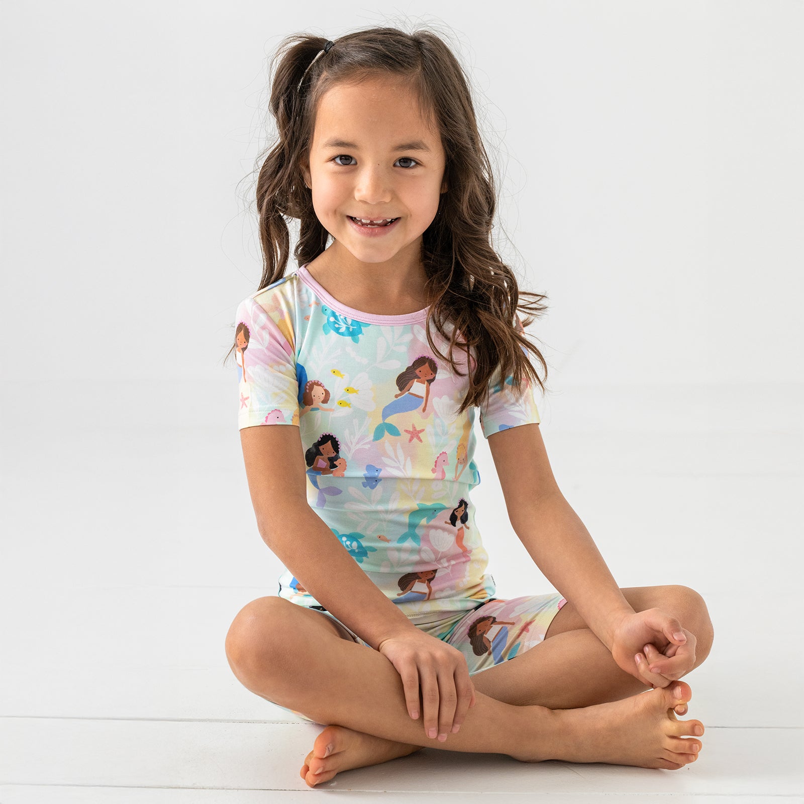 Alternate sitting child wearing the Mystic Mermaids Two-Piece Short Sleeve & Shorts Pajama Set