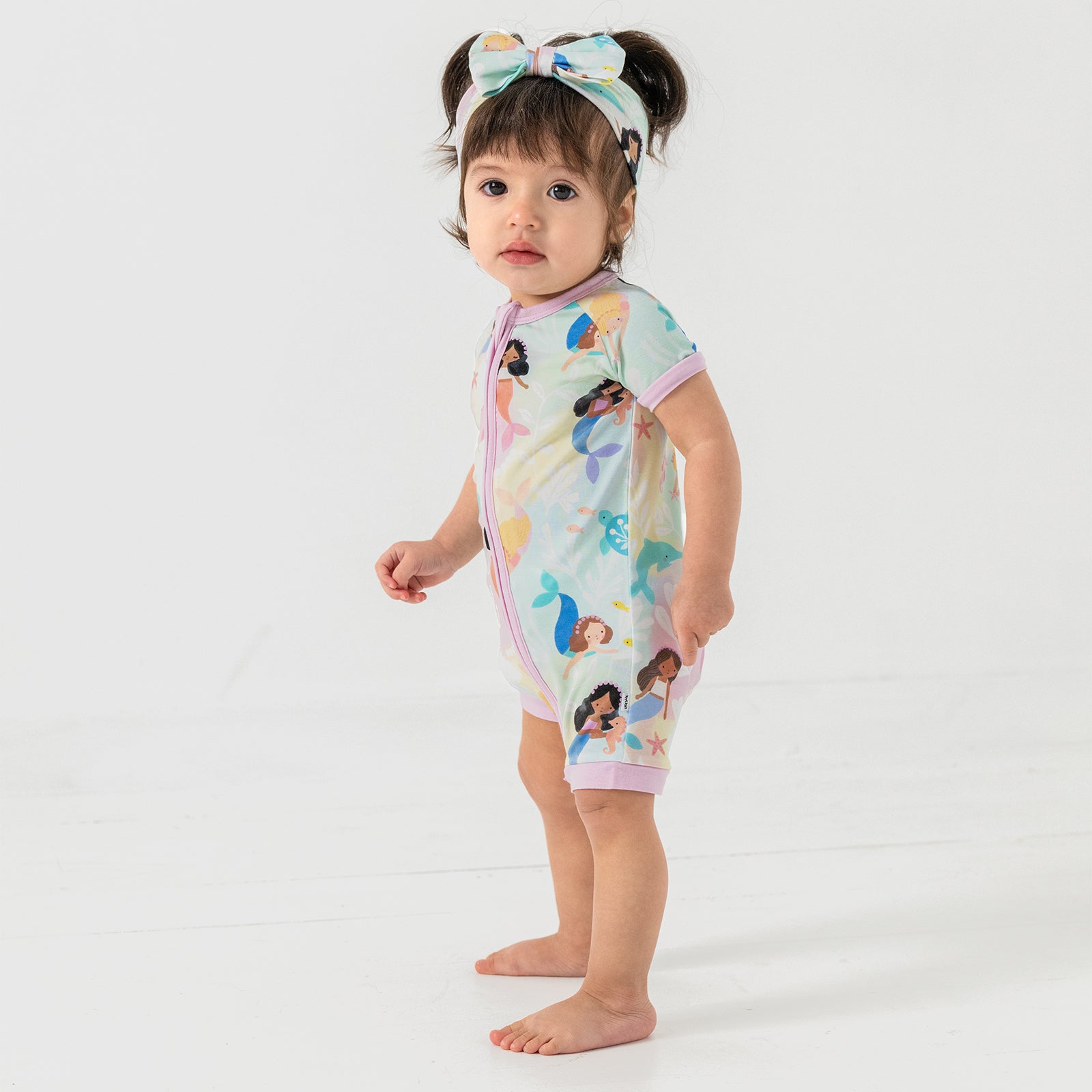 Standing child wearing the Mystic Mermaids Shorty Zippy and matching luxe bow headband