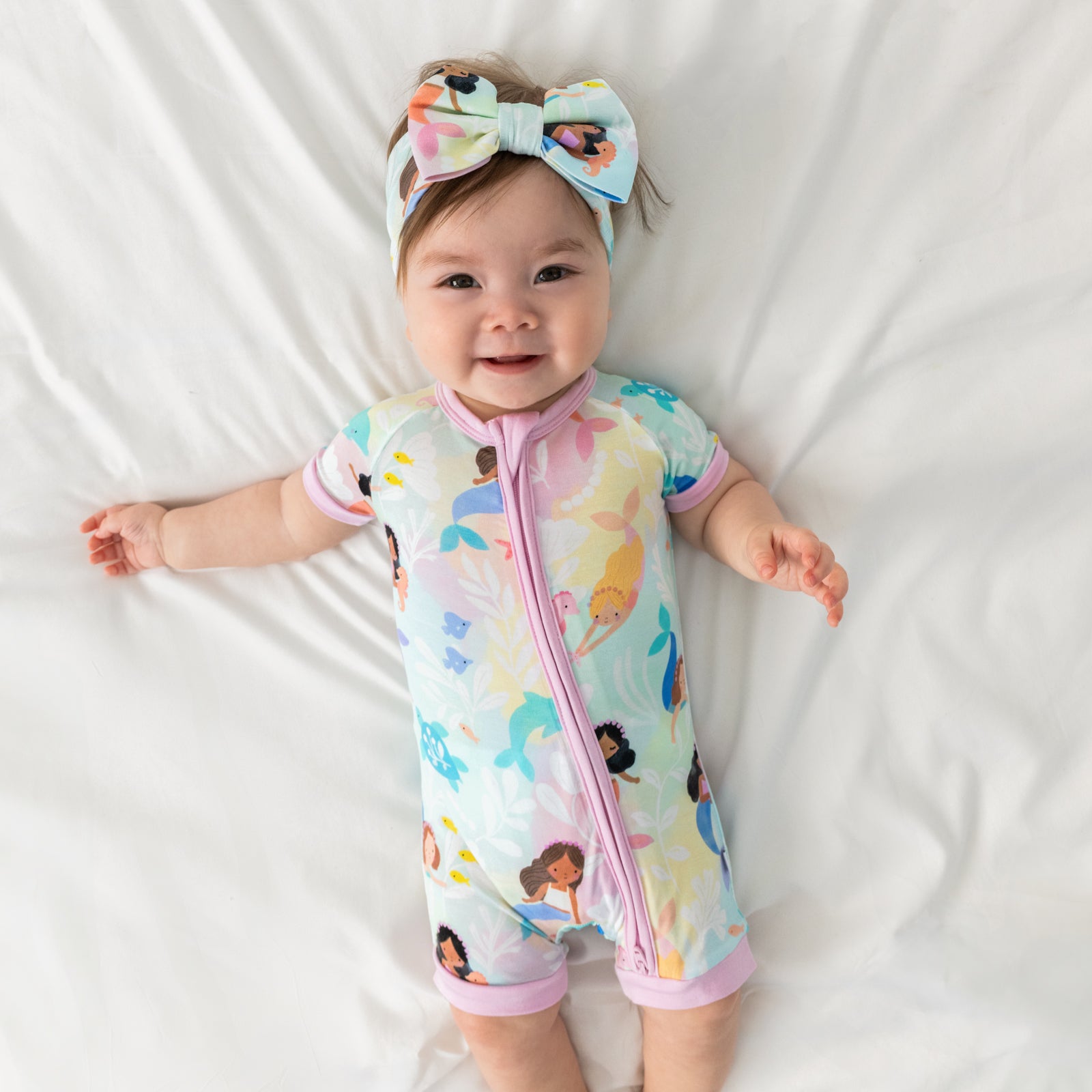 Alternate aerial view of child wearing the Mystic Mermaids Shorty Zippy with a matching luxe bow headband