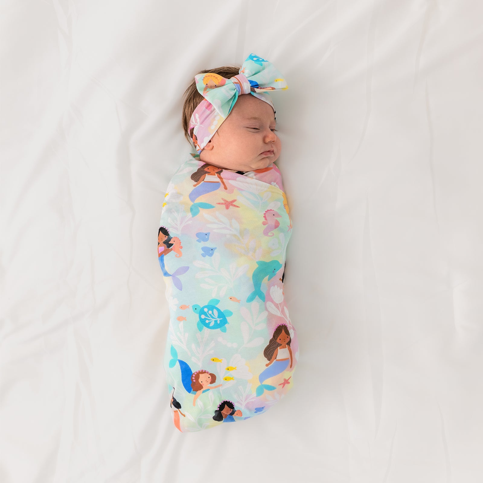 Aerial view of child wearing the Mystic Mermaids Swaddle & Luxe Bow Headband Set