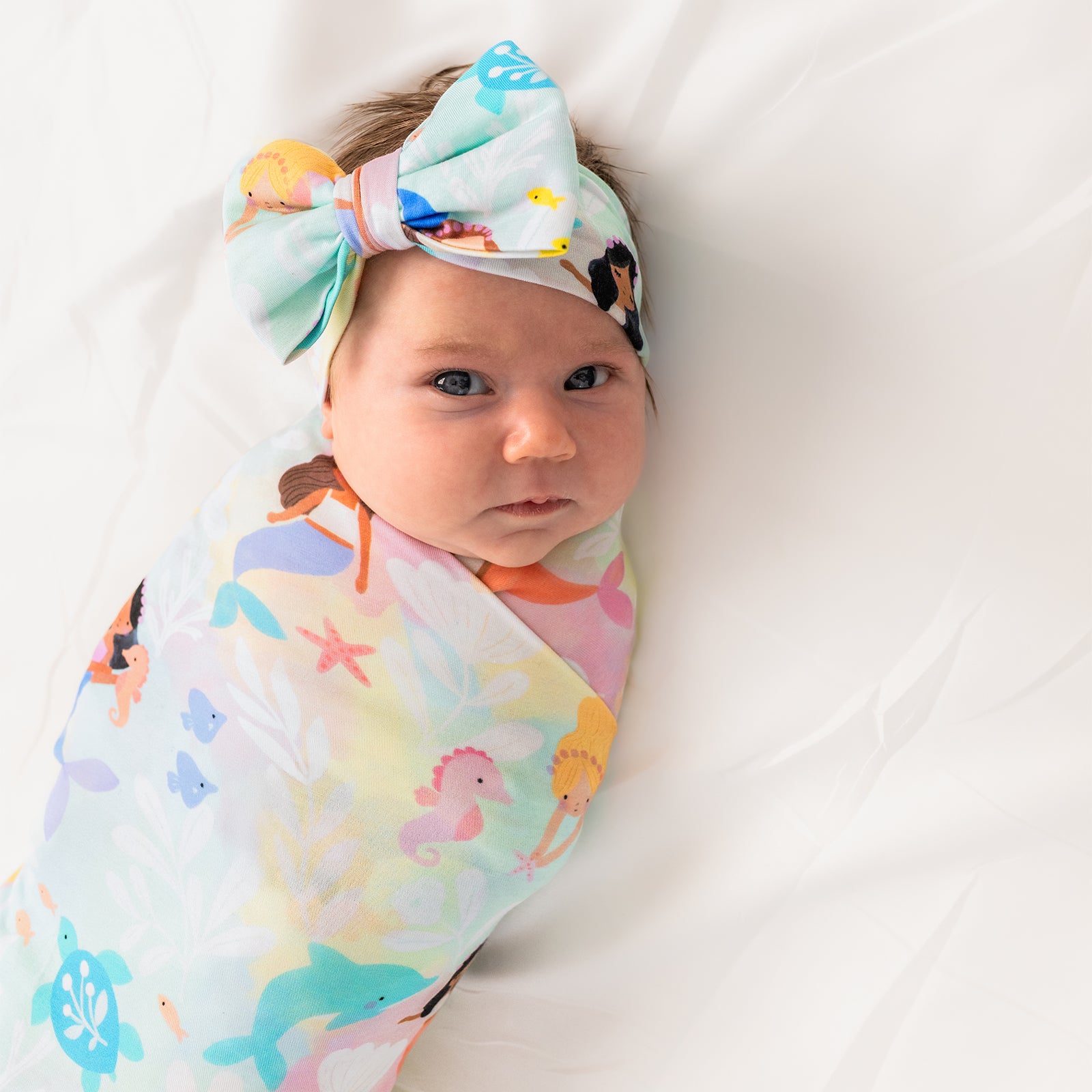 Close up of child wearing the Mystic Mermaids Swaddle & Luxe Bow Headband Set