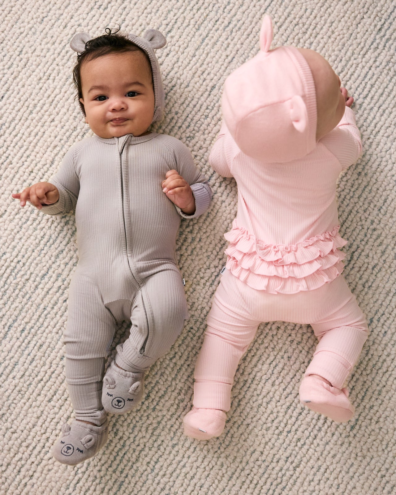 Aerial view of two newborns wearing zipper pajamas from the Newborn Capsule