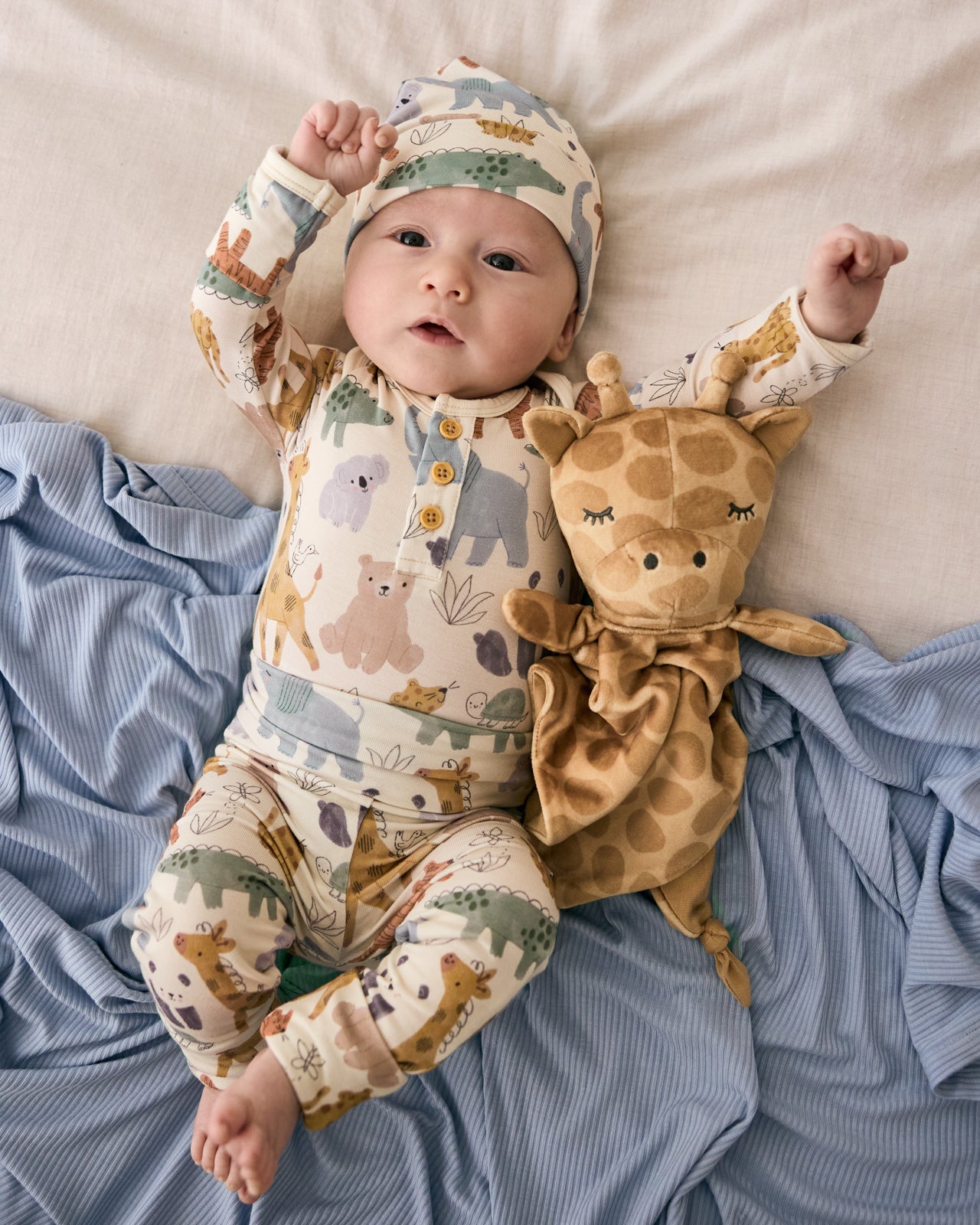 Aerial view of baby wearing the Sweet Safari Fold-Over Leggings snuggled with a giraffe lovey