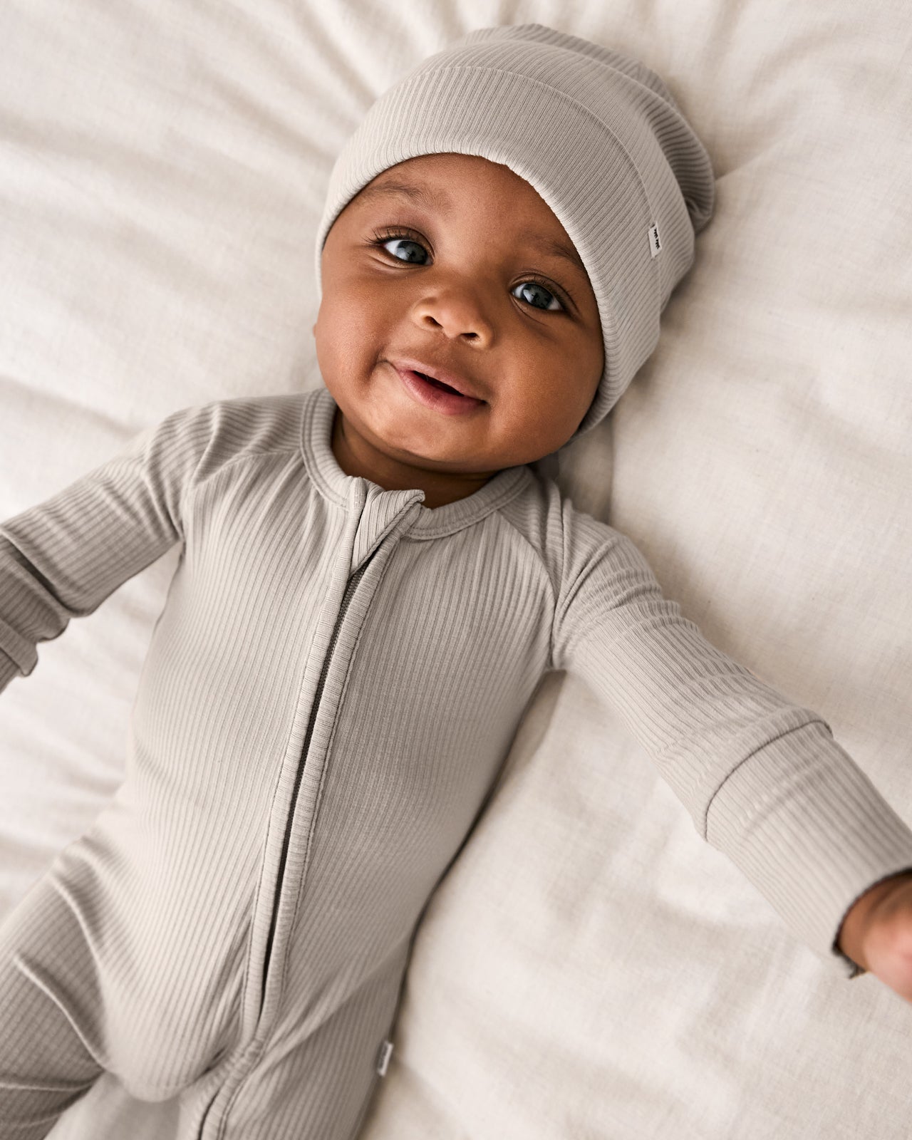 Close up of newborn wearing the Dove Gray Ribbed Zippy and matching infant beanie