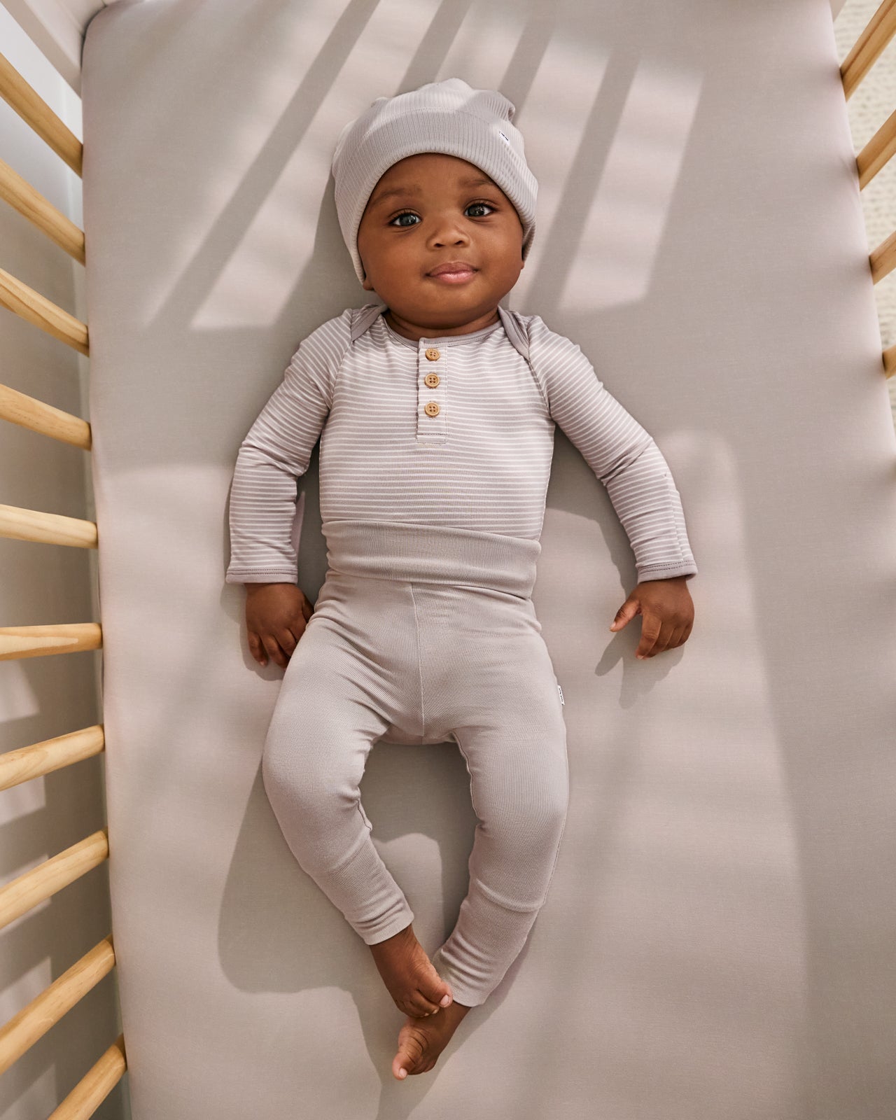 Aerial view of baby wearing the Dove Gray Fold-Over Legging on a gray crib sheet
