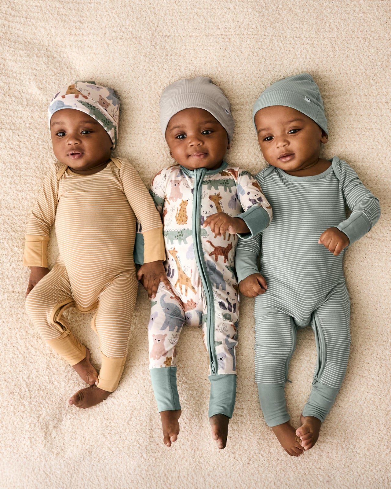 Aerial view of three babies wearing styles from the Newborn Capsule
