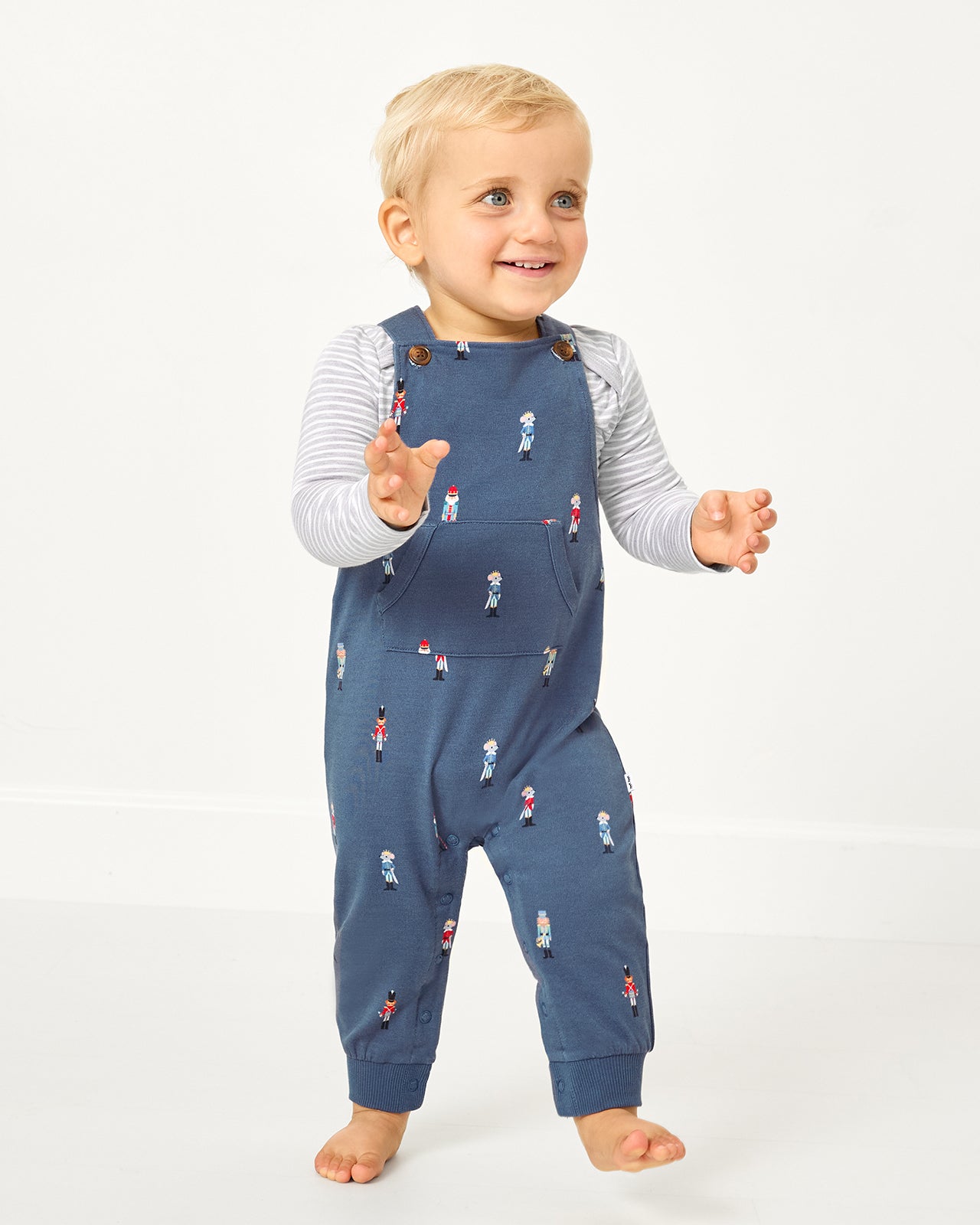 Walking toddler wearing the Nutcracker March Overall Romper