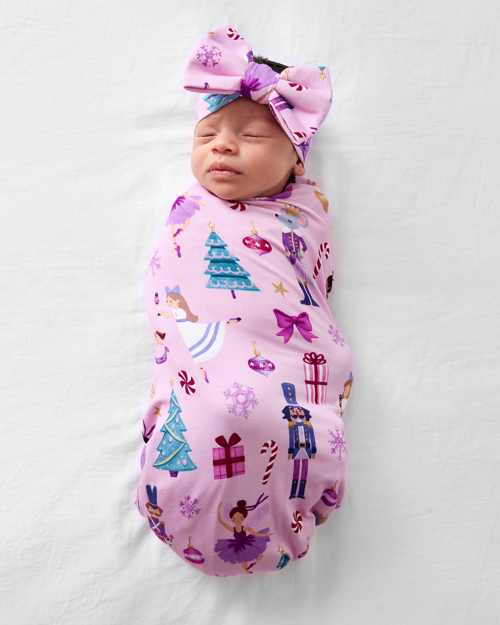 Aerial view of baby wearing the Nutcracker Ballet Swaddle & Luxe Bow Headband Set