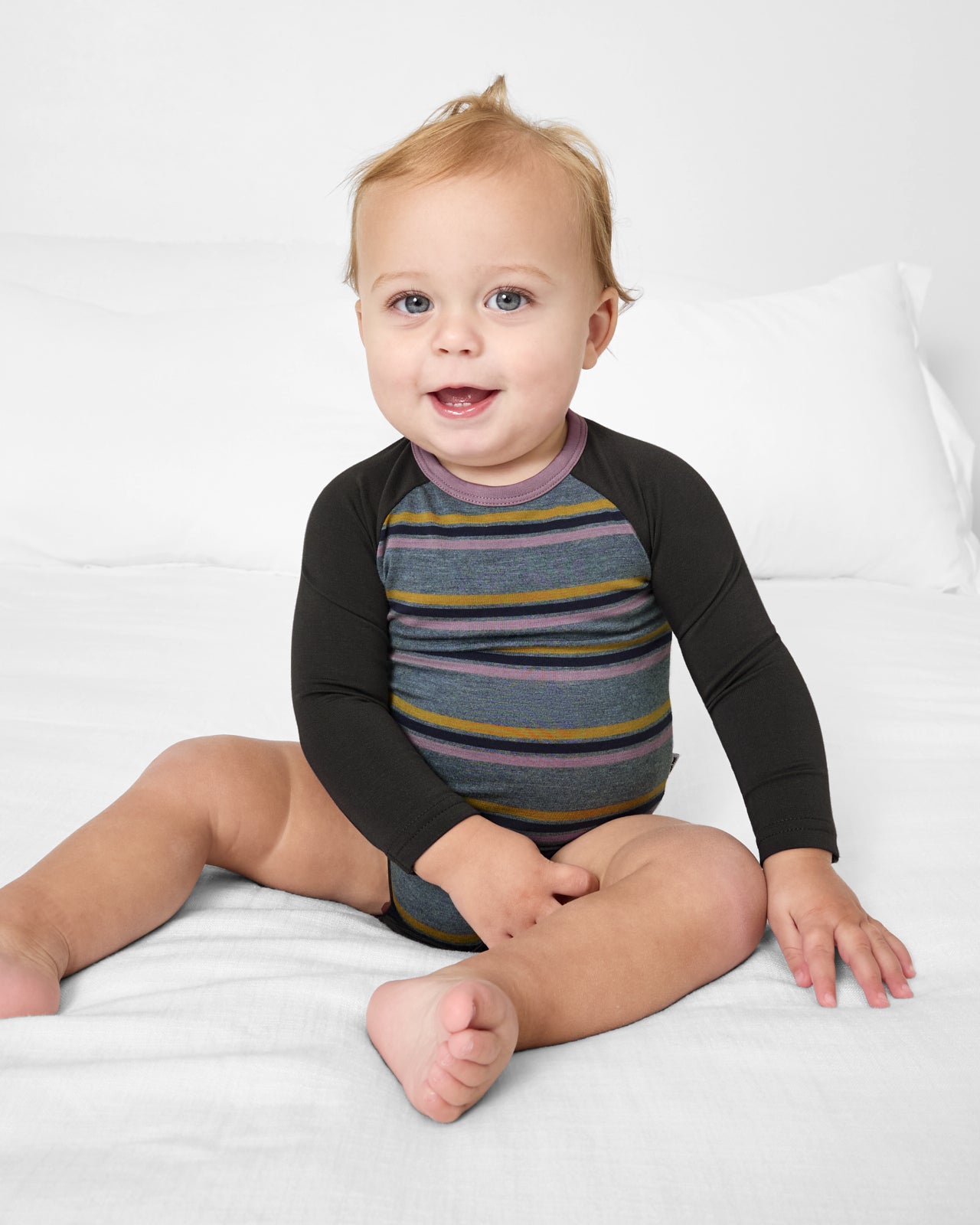 Sitting baby wearing the Ollie Stripe Raglan Bodysuit