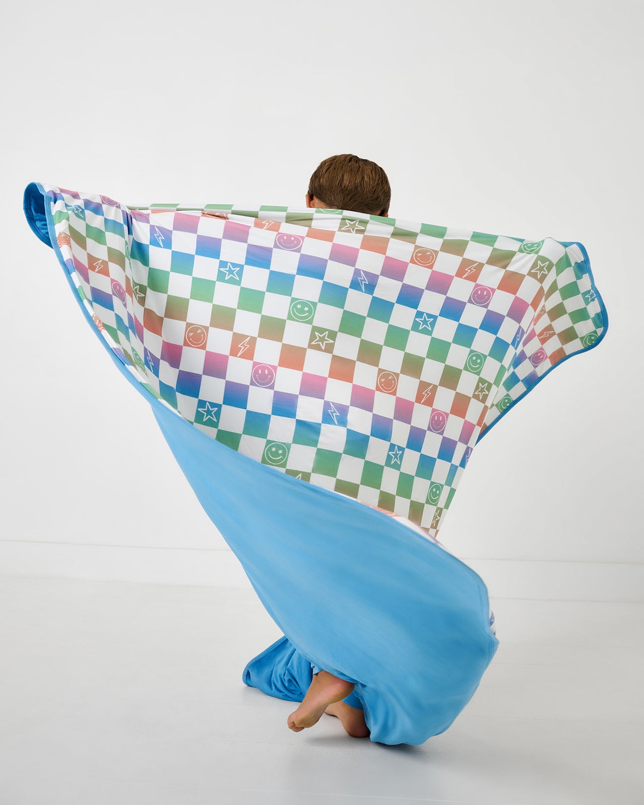 Child in motion holding up the Ombre Cheery Checks Large Cloud Blanket®