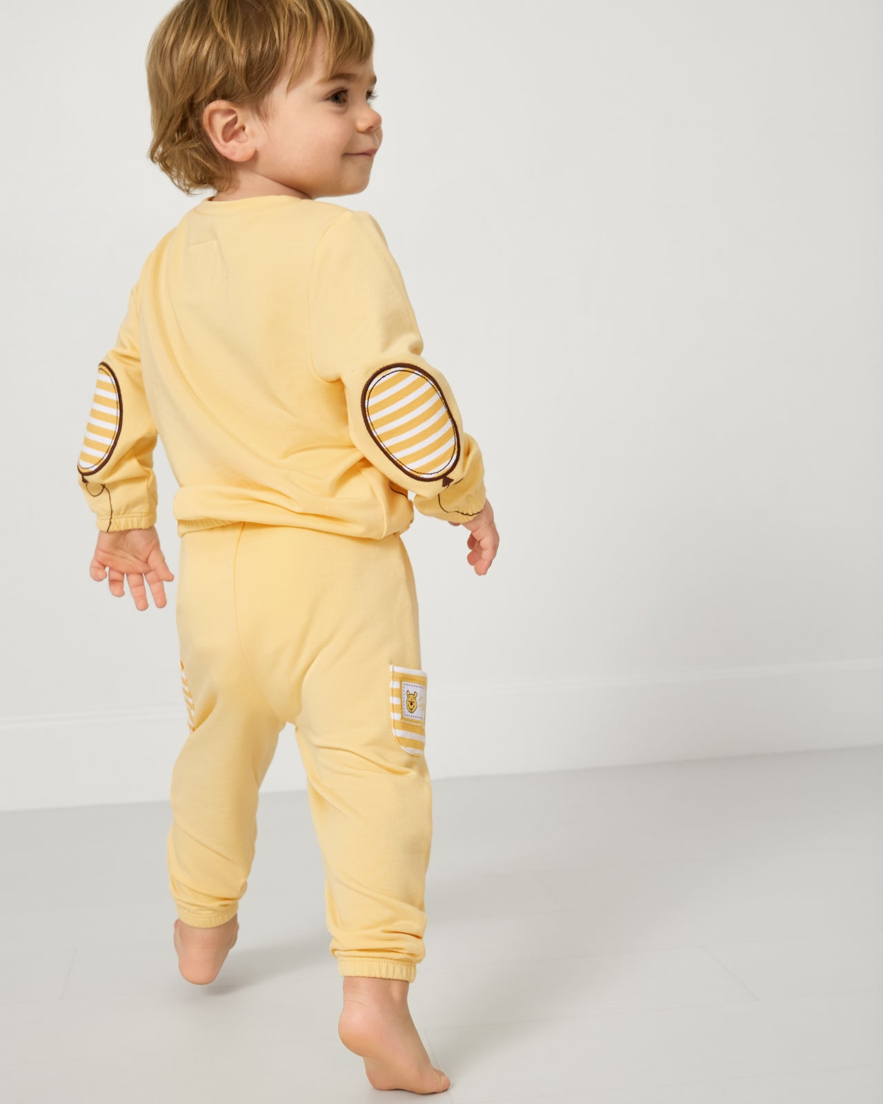 Back view of boy wearing the Disney Winnie The Pooh Cinched Crewneck and Jogger