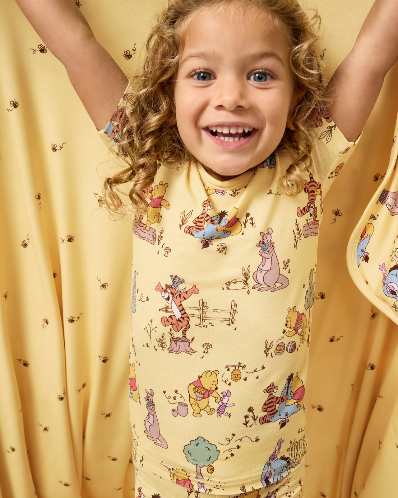 Close up of girl holding the Disney Playtime With Pooh Large Cloud Blanket® showing the honey bee print side