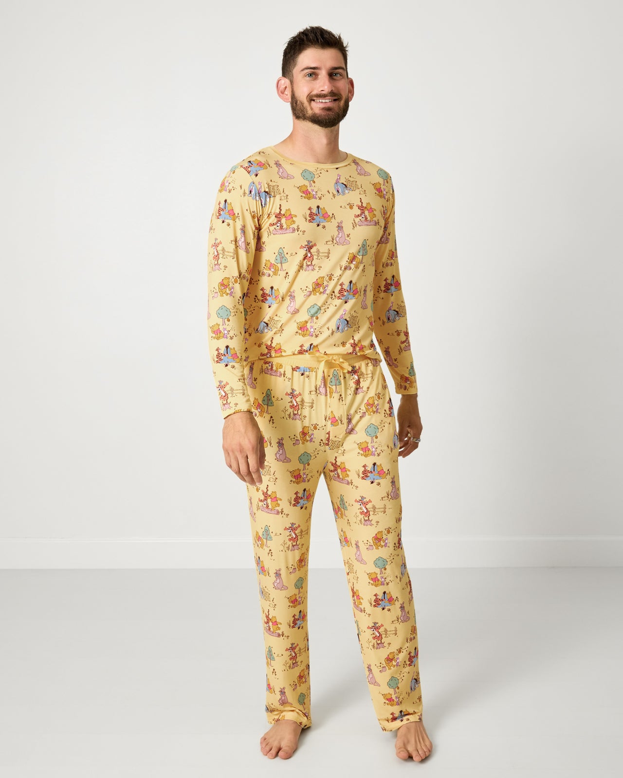 Man wearing the Disney Playtime With Pooh Men's Long Sleeve Pajama Top and Pants