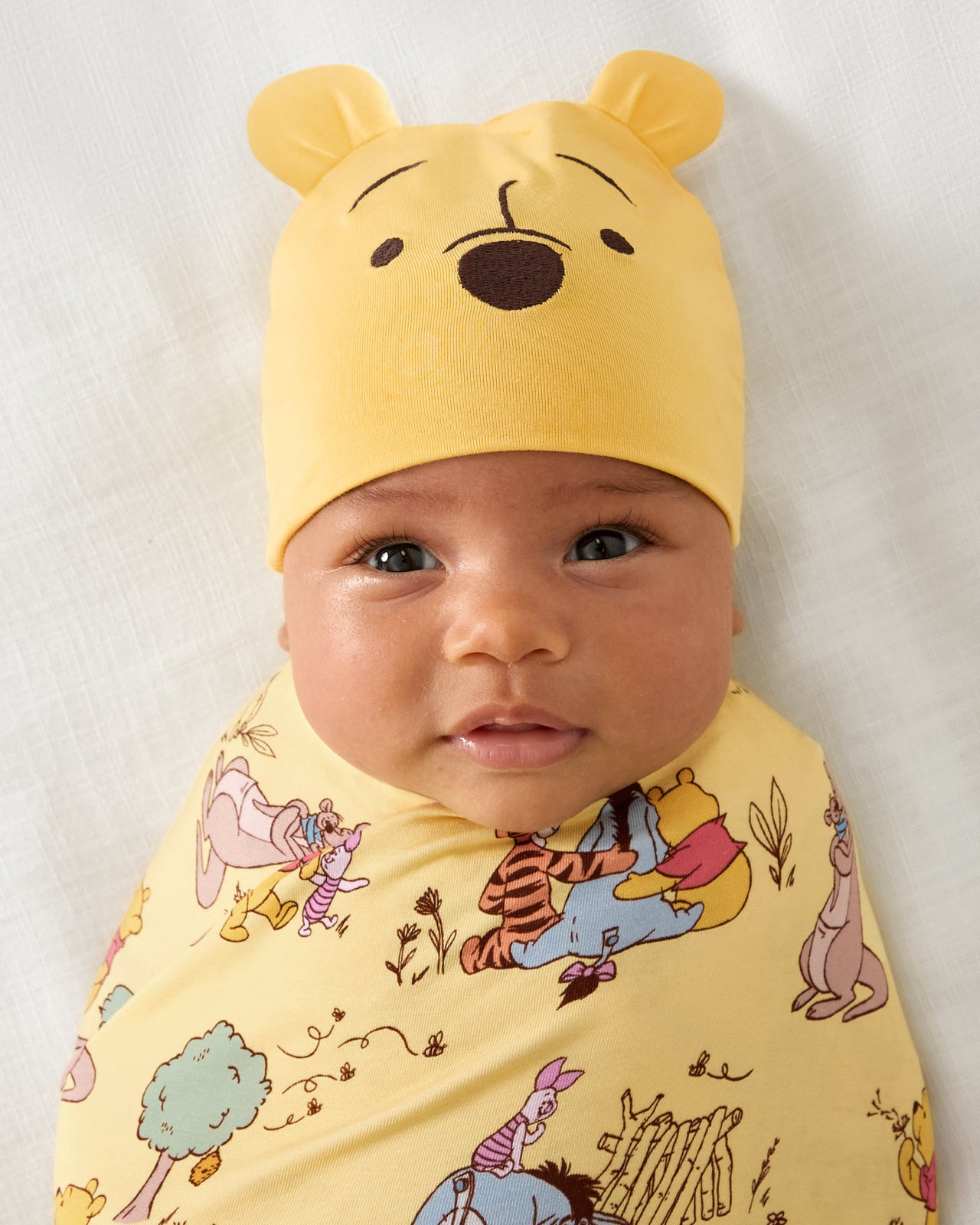 Close up of baby wearing the Disney Playtime With Pooh Swaddle & Hat Set
