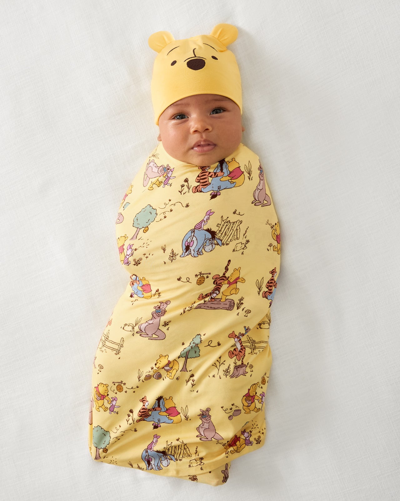 Aerial view of baby wearing the Disney Playtime With Pooh Swaddle & Hat Set