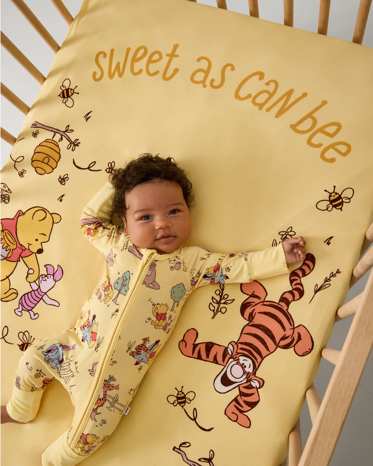 Baby laying in a crib with the Disney Sweet As Can Bee Fitted Crib Sheet