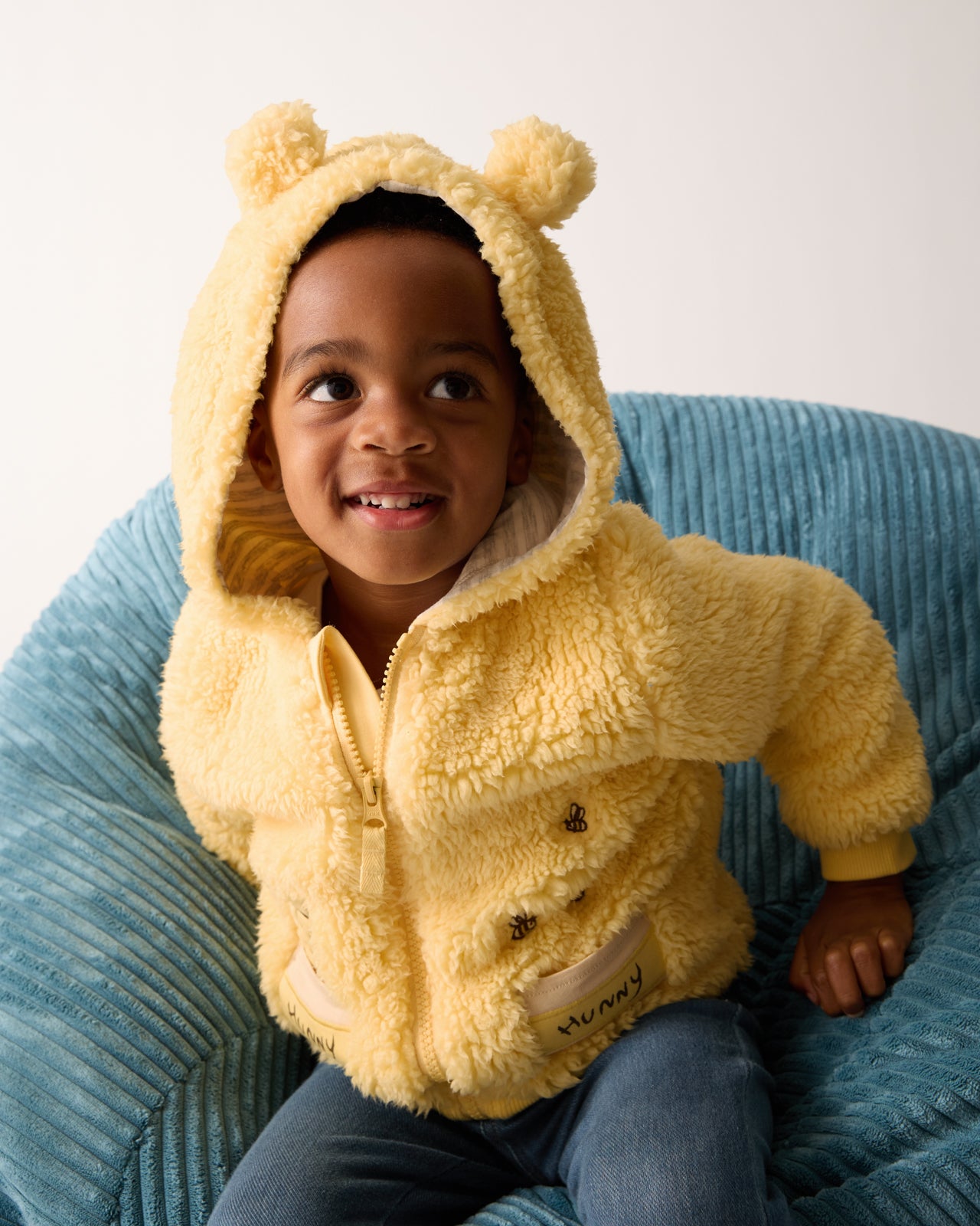 Boy wearing the Disney Winnie the Pooh Sherpa Zip Hoodie on a blue chair