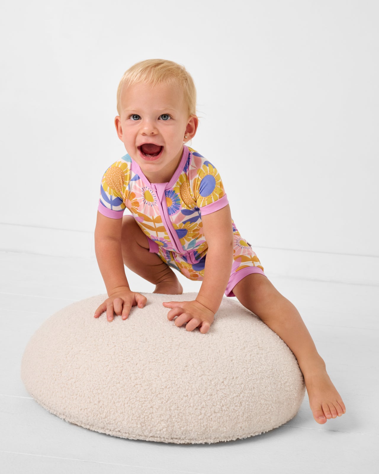 Toddler crawling on an ottoman wearing the Petal Power Shorty Zippy