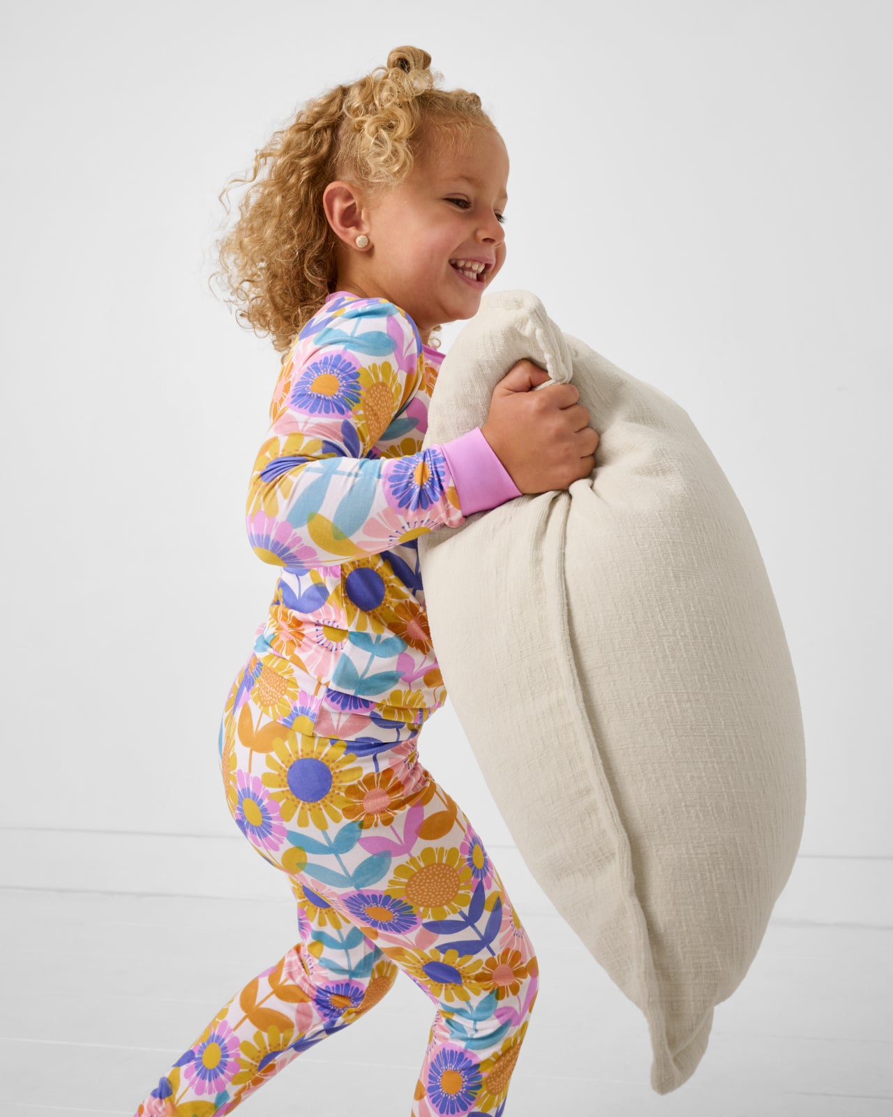 Child holding a pillow wearing the Petal Power Two-Piece Pajama Set