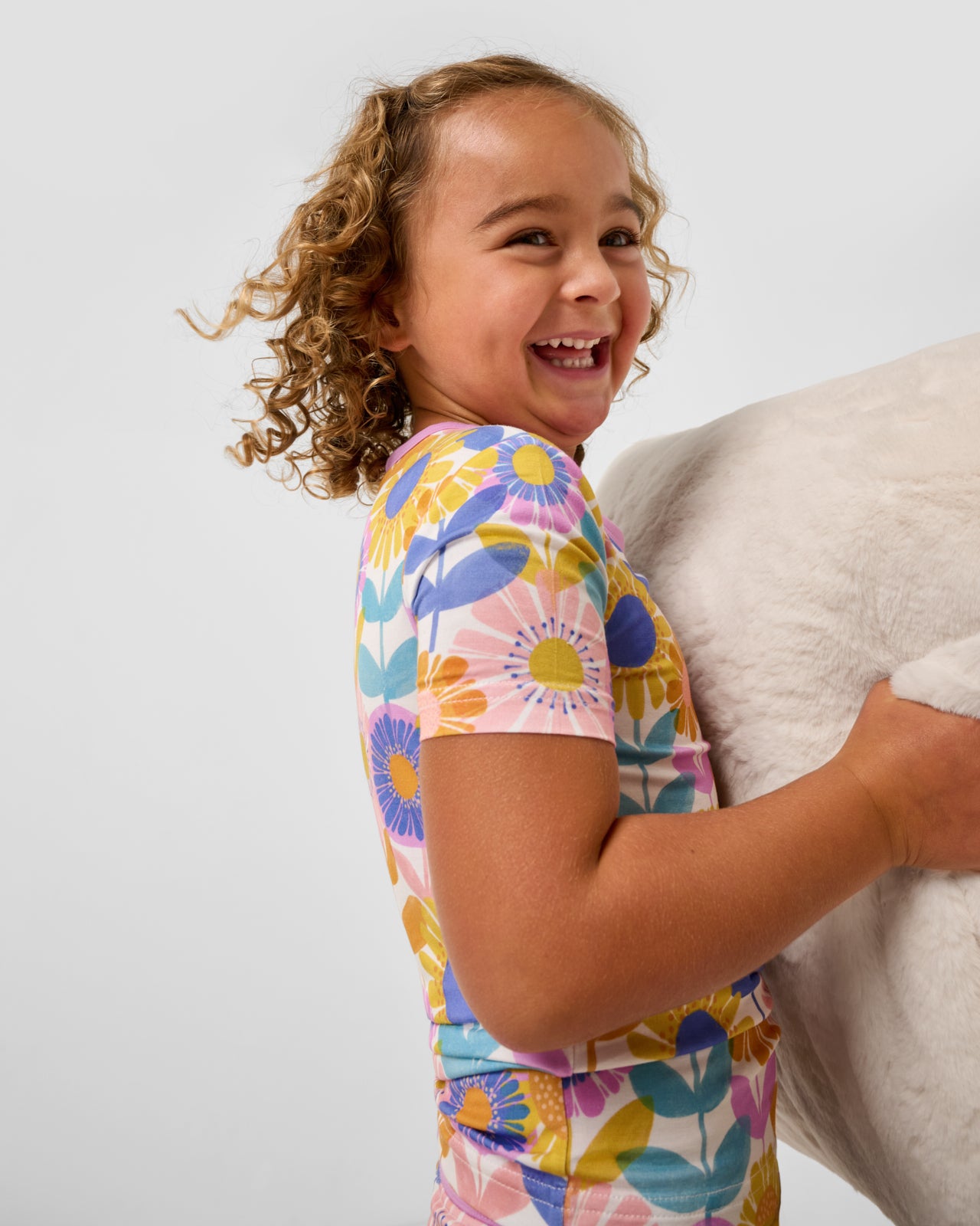 Girl wearing the Petal Power Two-Piece Short Sleeve & Shorts Pajama Set holding a pillow