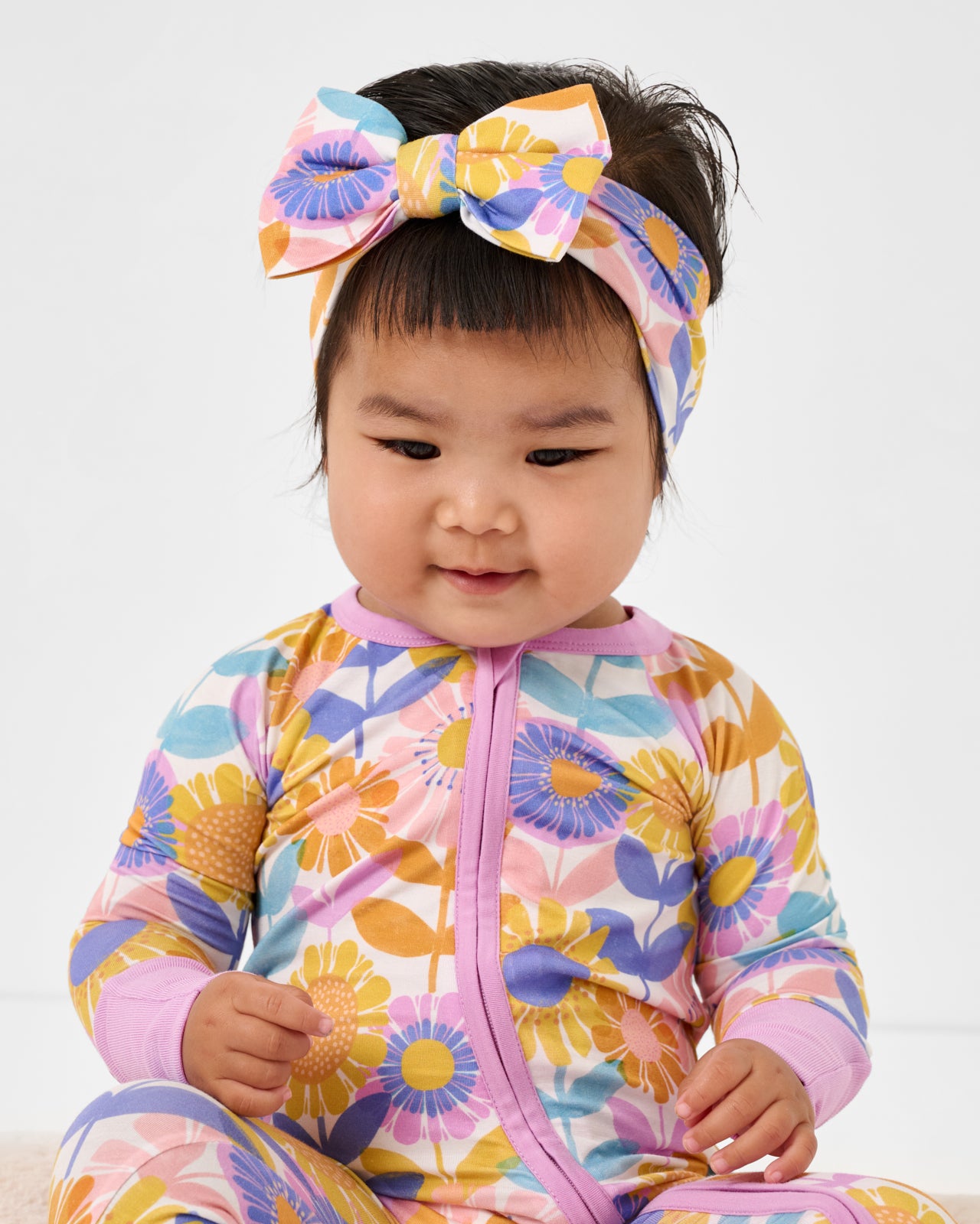 Close up of baby wearing the Petal Power Zippy and Luxe Bow Headband