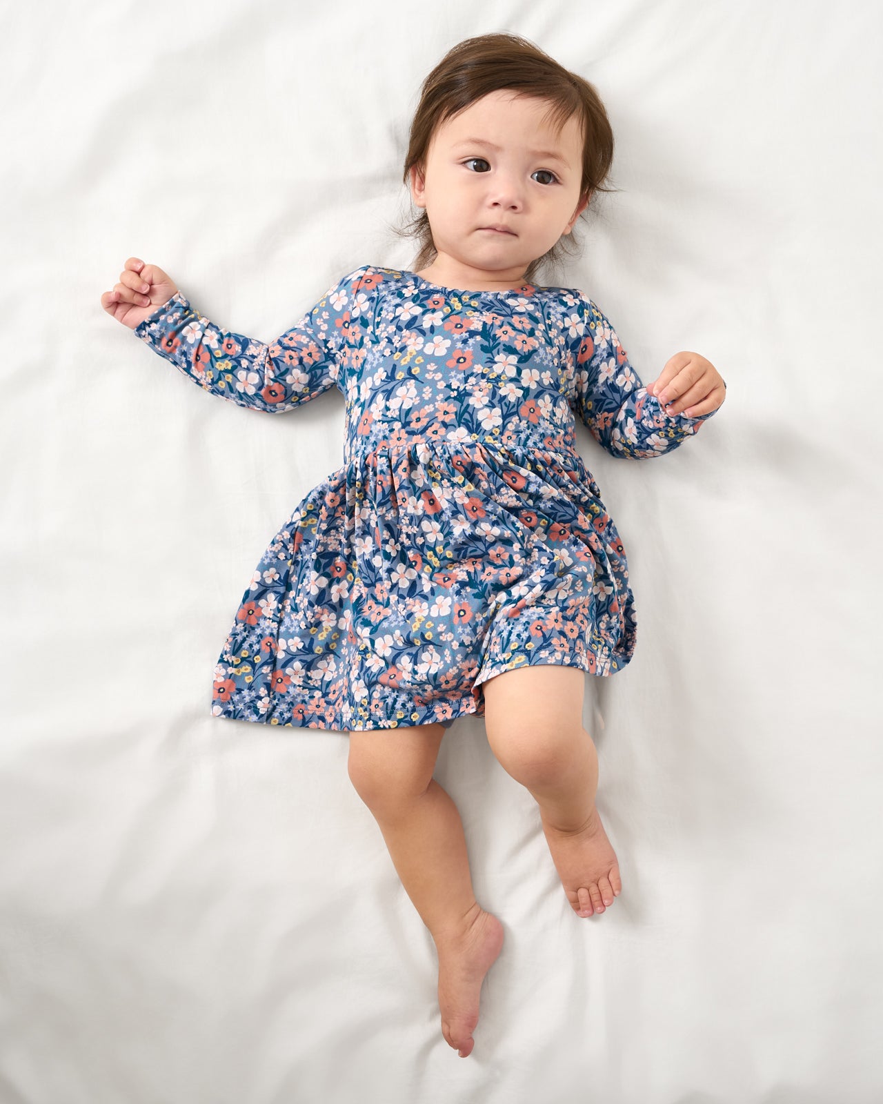 Aerial view of baby wearing the Petite Petals Bow Back Skater Dress with Bodysuit