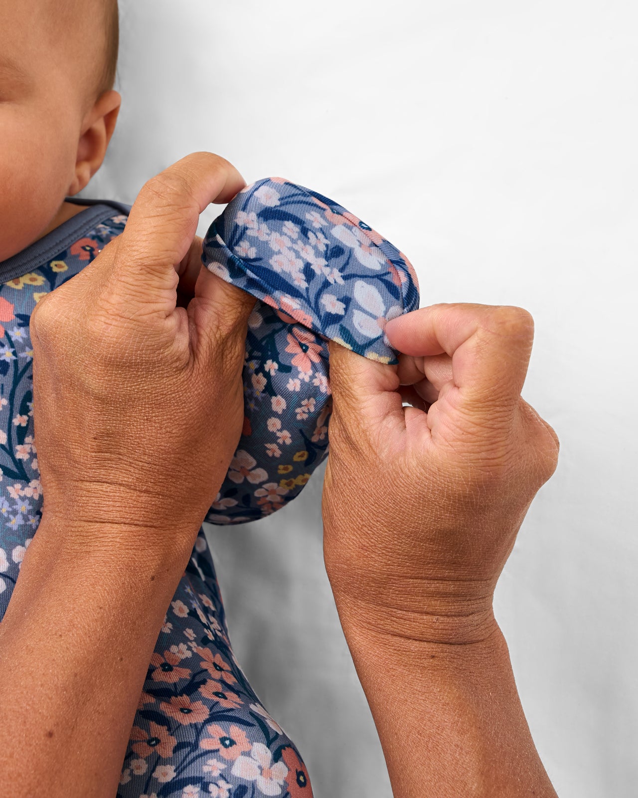 Adult demonstrating the fold-over mittens on the Petite Petals Infant Gown