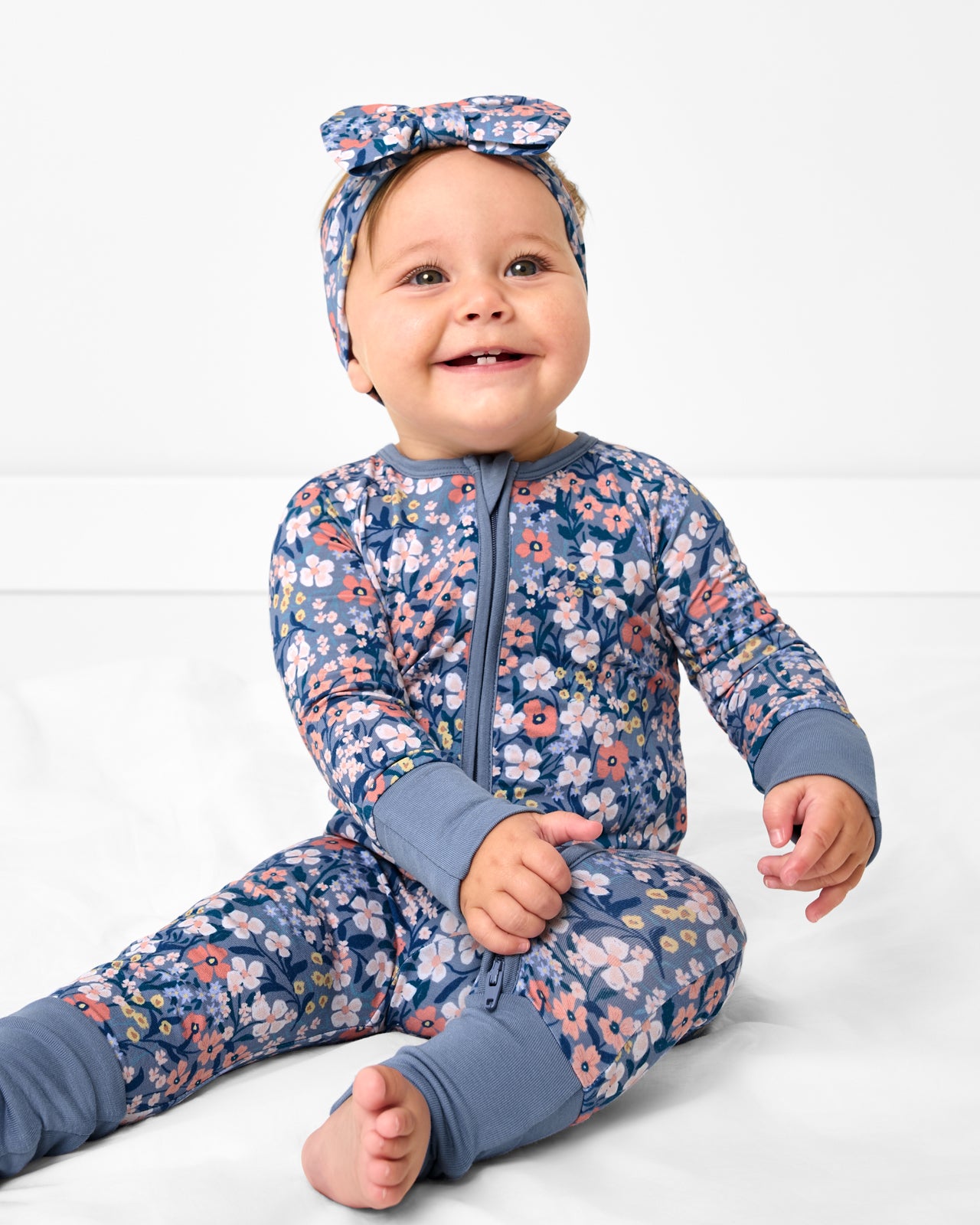 Baby wearing the Petite Petals Zippy with a matching bow headband