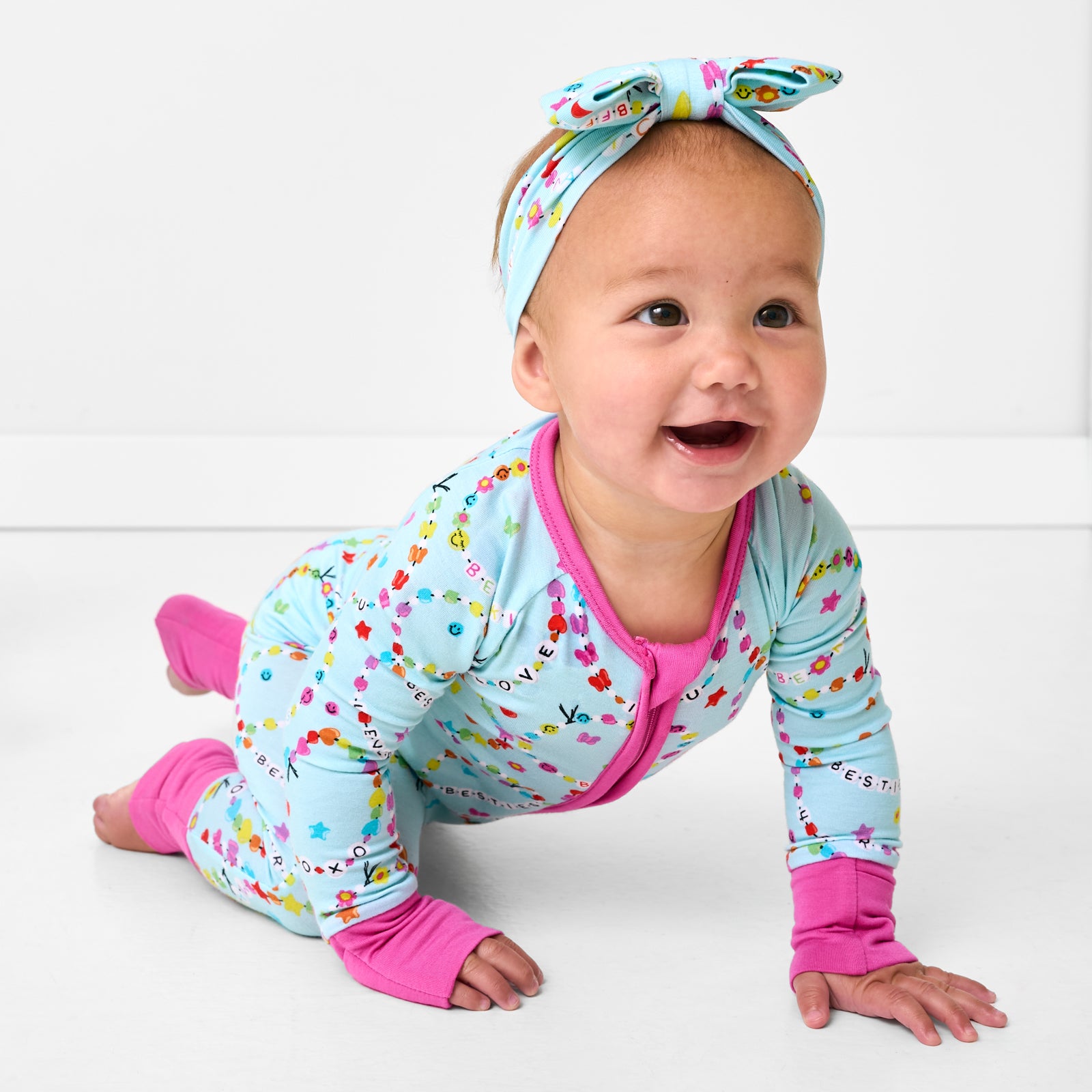 Crawling child wearing the Friends Forever Luxe Bow Headband and matching friendship bracelet themed pjs