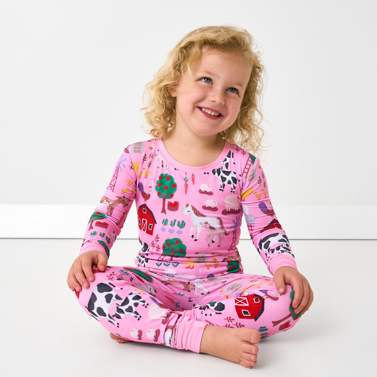 Sitting child wearing the Pink Farm Fam Two-Piece Pajama Set