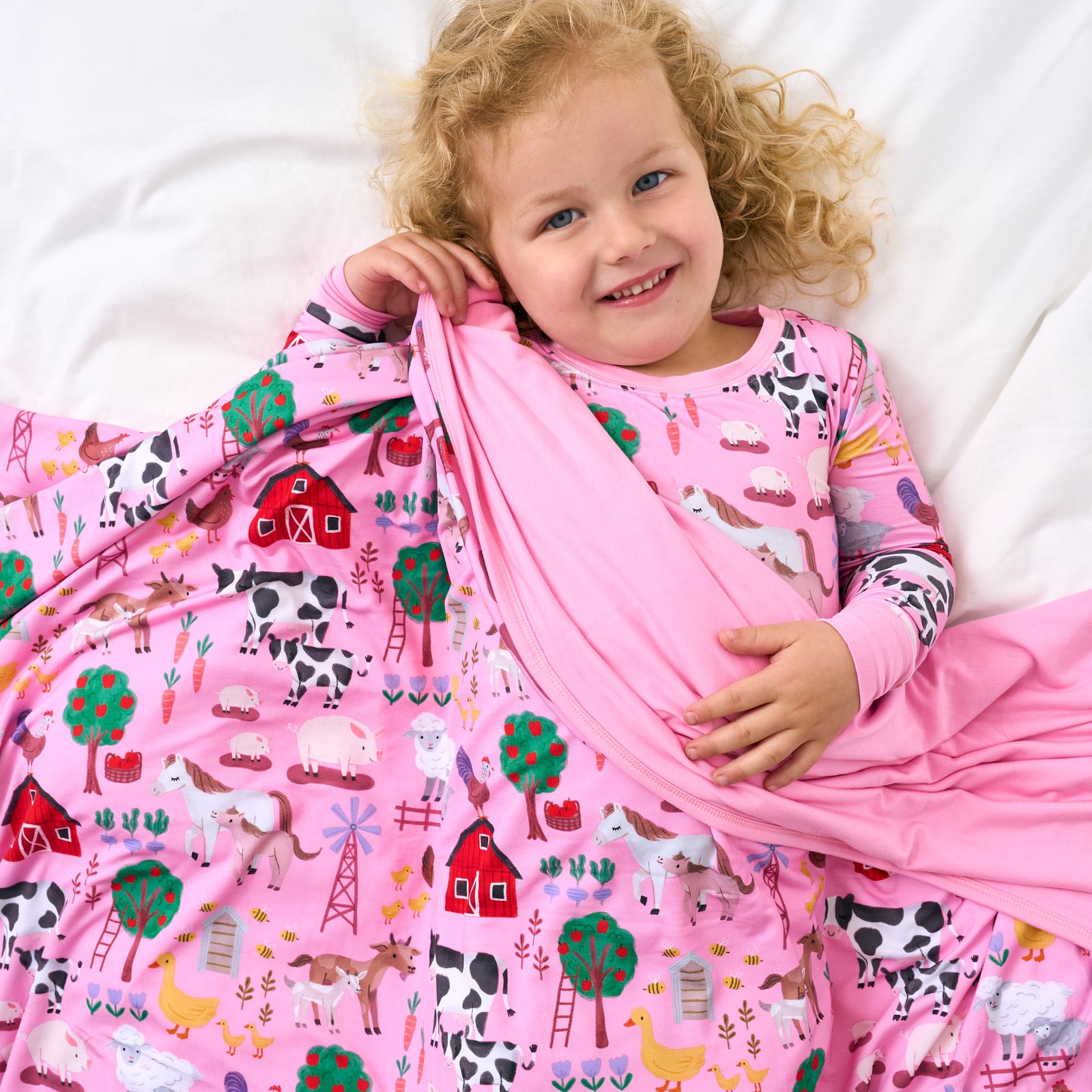 Aerial view of child laying with the Pink Farm Fam Large Cloud Blanket®