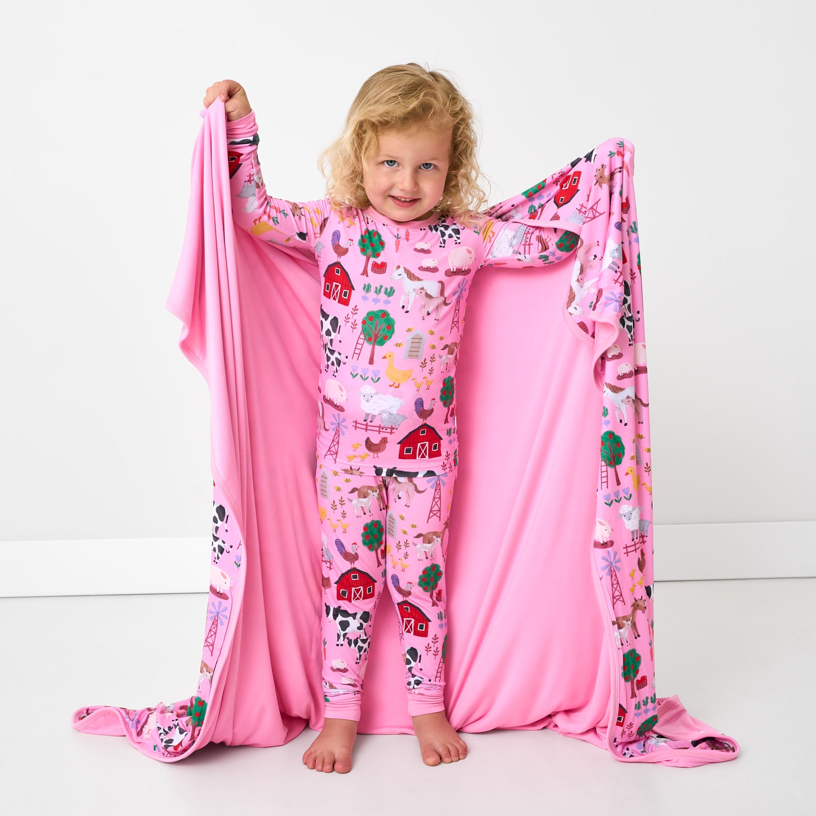 Standing child holding up the Pink Farm Fam Large Cloud Blanket®