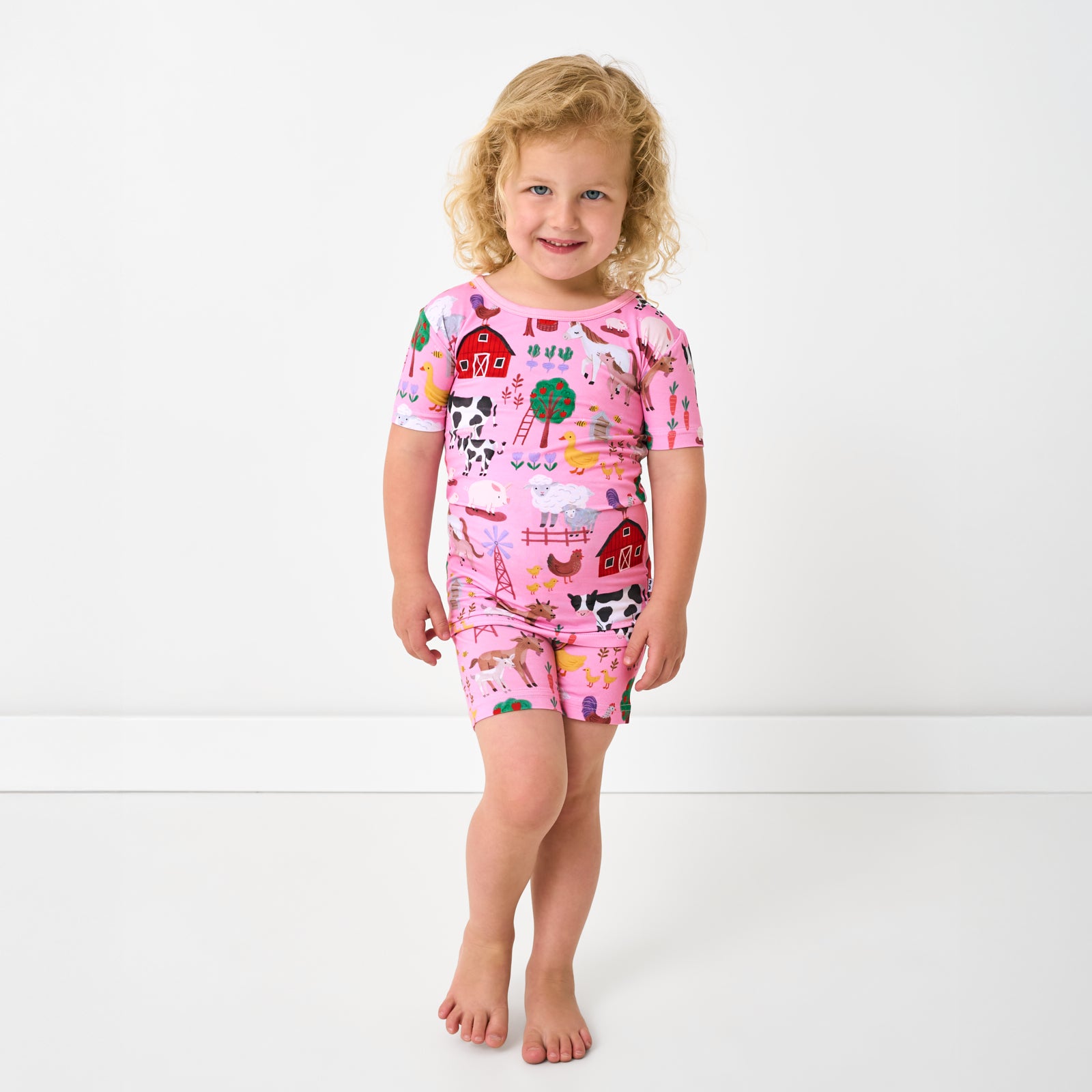 Standing child wearing the Pink Farm Fam Two-Piece Short Sleeve & Shorts Pajama Set