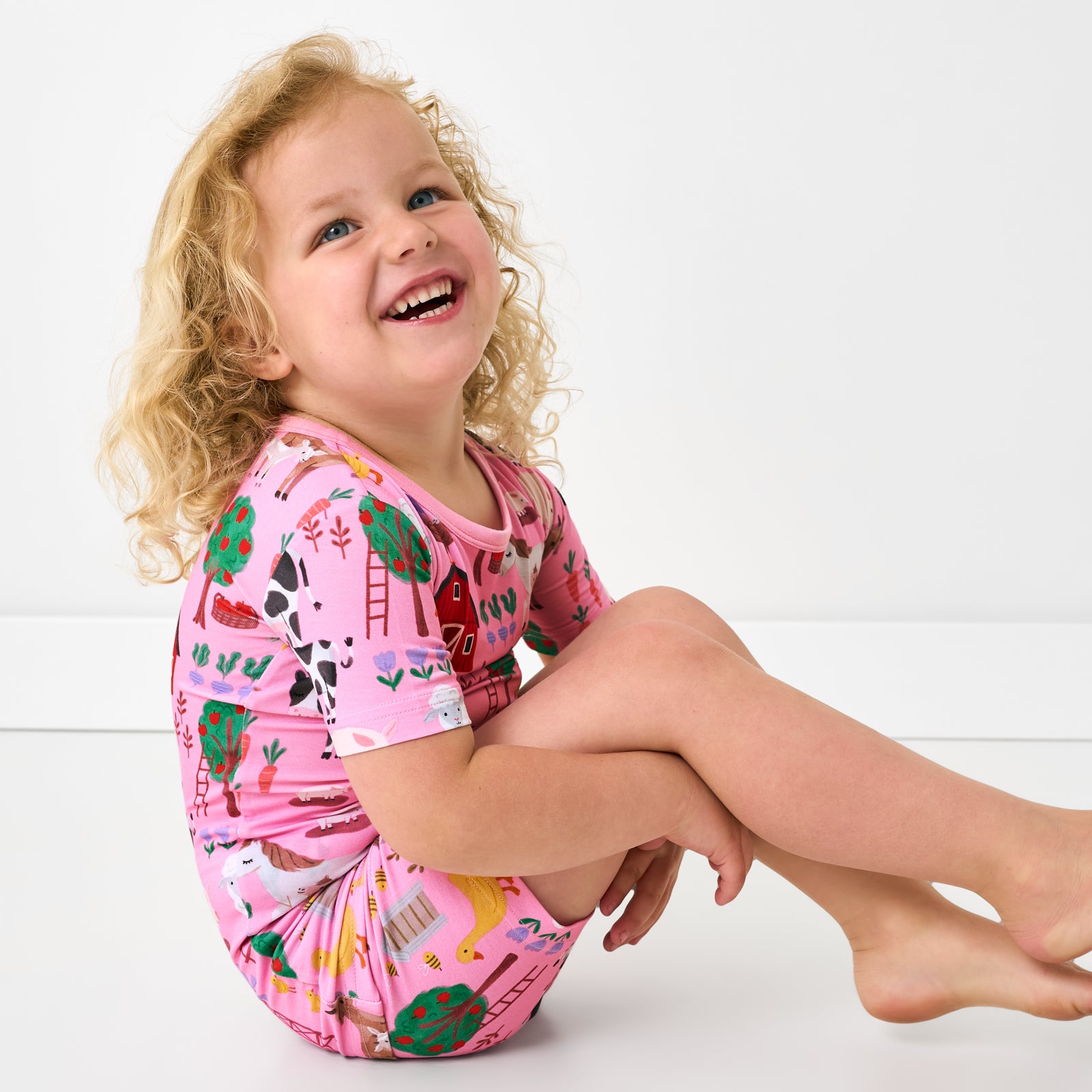 Sitting child wearing the Pink Farm Fam Two-Piece Short Sleeve & Shorts Pajama Set