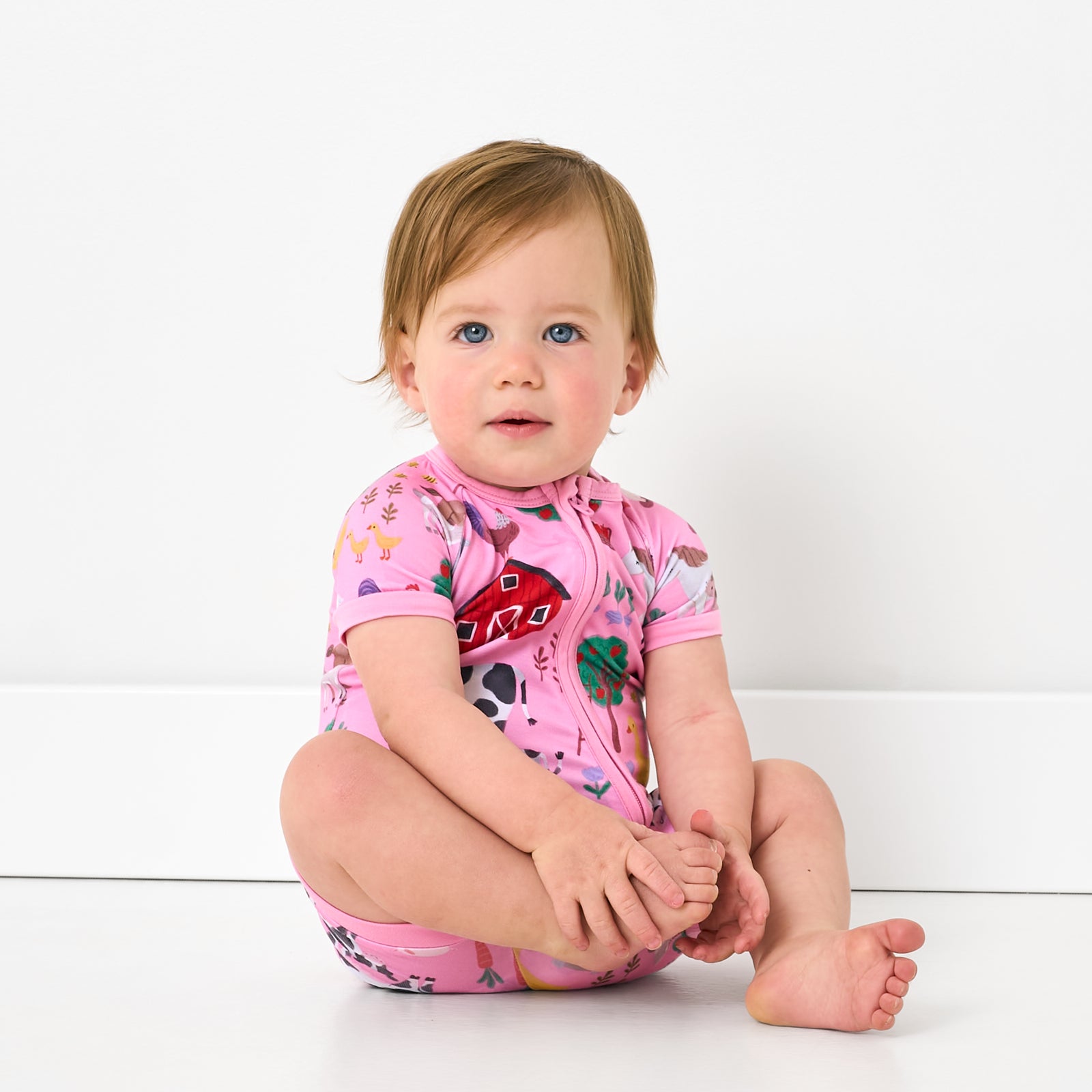 Sitting baby wearing the Pink Farm Fam Shorty Zippy