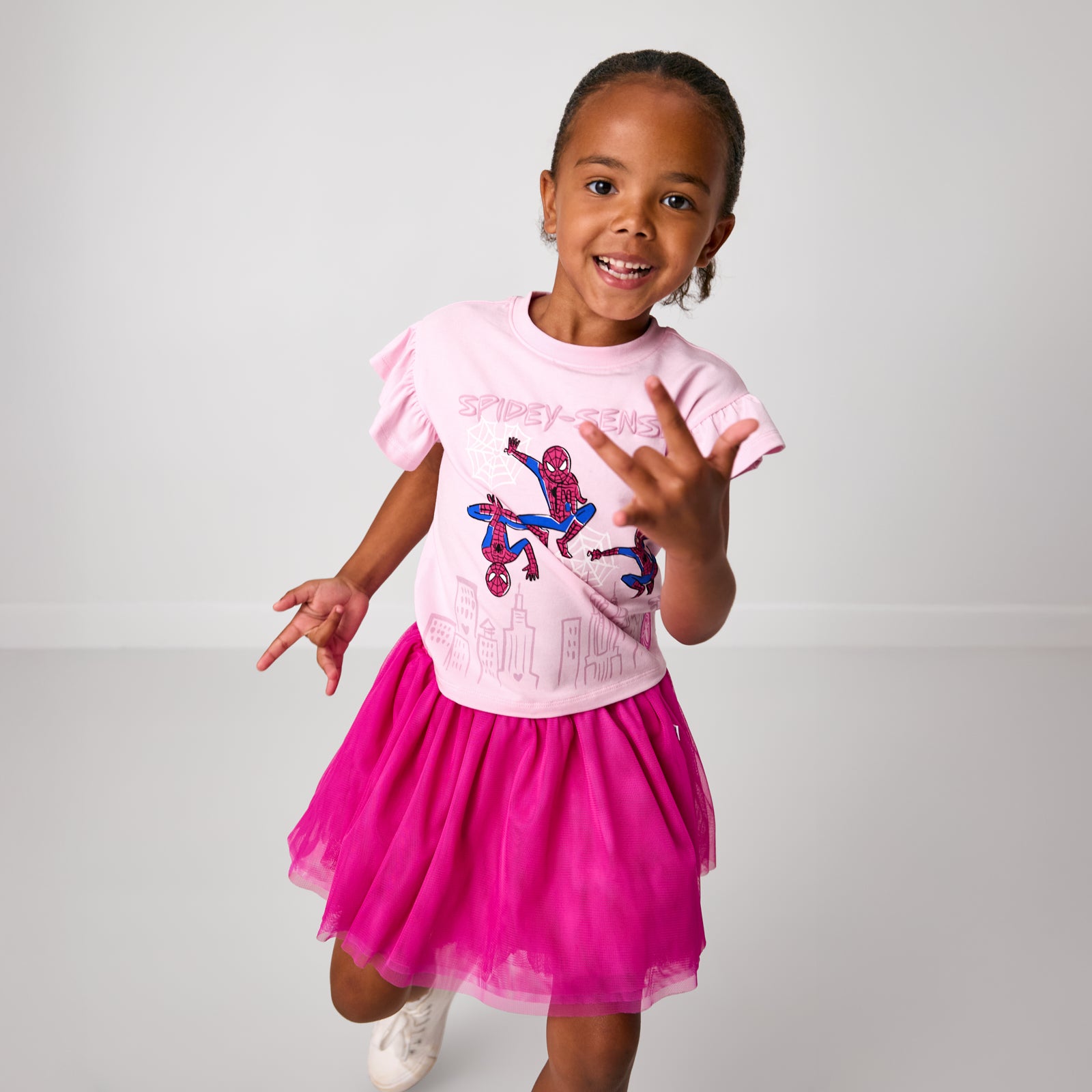 Posing child wearing the Spidey Sense Flutter Tee with the electric fuchsia skirt