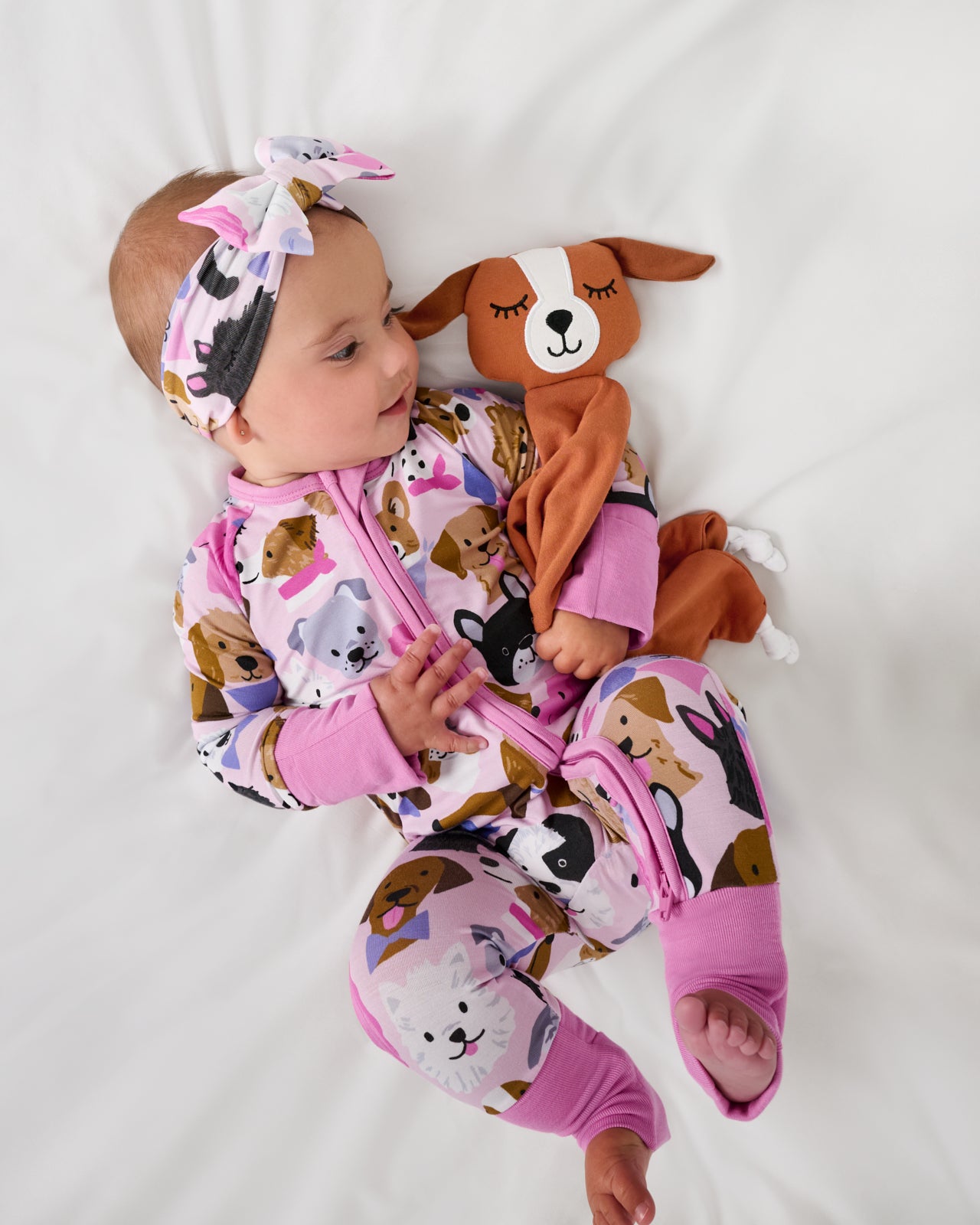 Aerial view of baby wearing the Pink Puppy Parade Zippy holding a puppy lovey