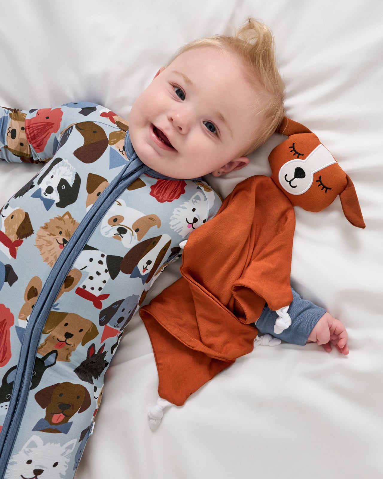 Aerial view of baby wearing the Gray Puppy Parade Zippy laying with a puppy lovey