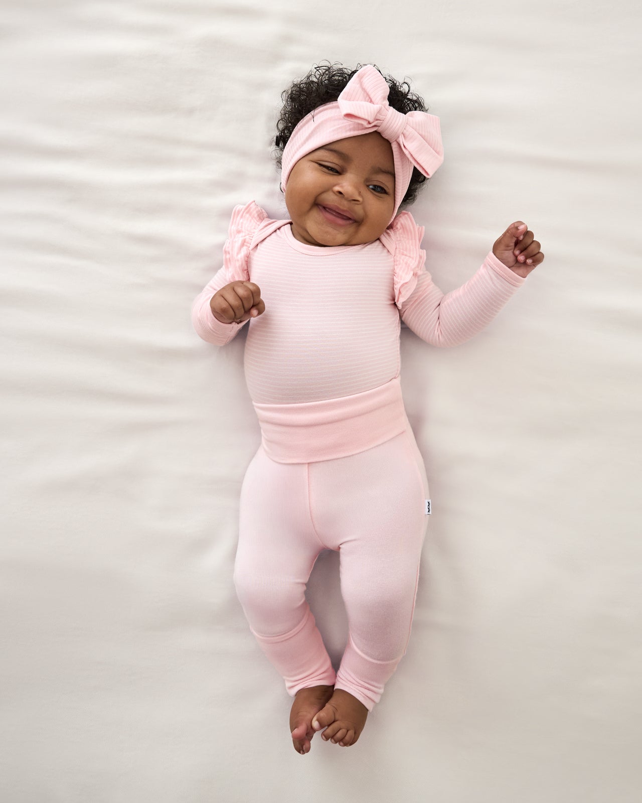 Aerial view of newborn wearing the Prima Pink Fold Over Legging with a flutter bodysuit