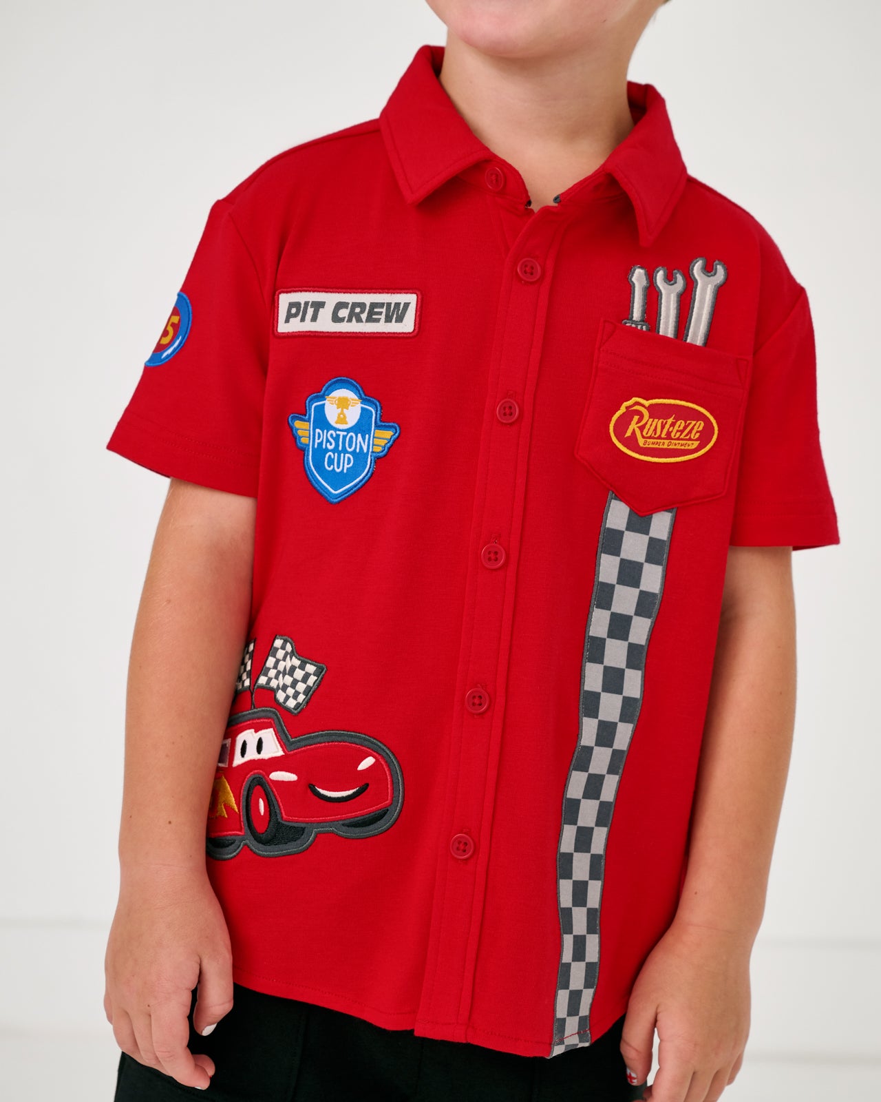 Close up of boy wearing the Disney & Pixar Piston Cup Button Down Polo
